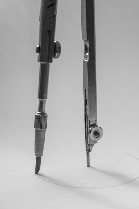 Close-up of a vintage drawing compass on white paper.