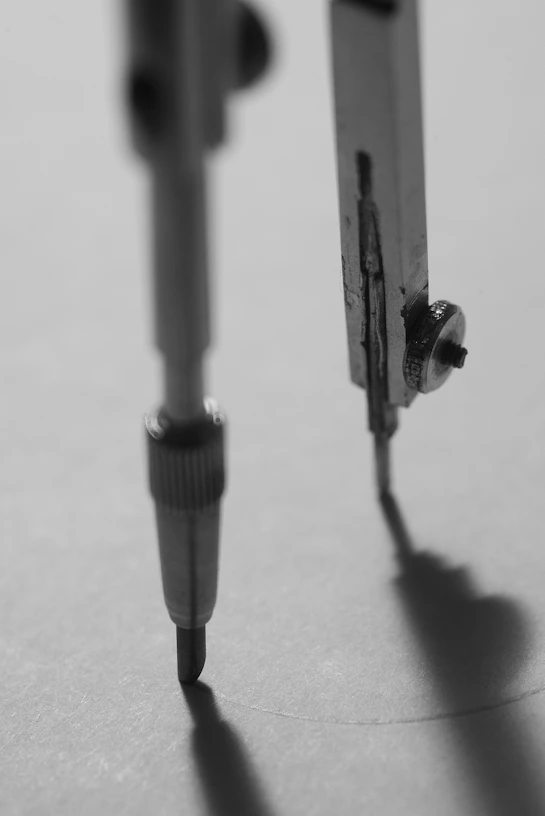 Close-up of a compass drawing a circle on paper