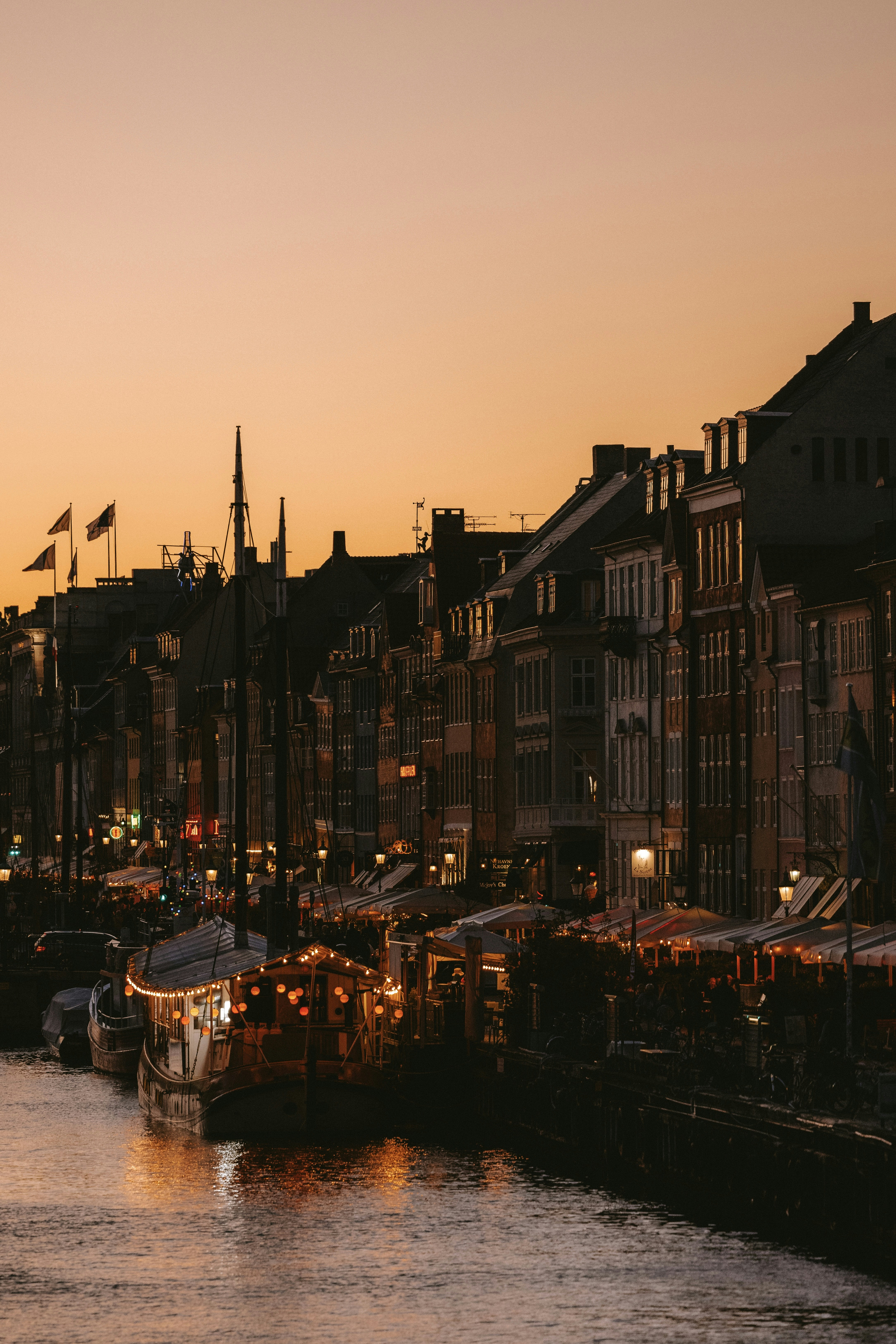 City buildings and boats along a canal at dusk.