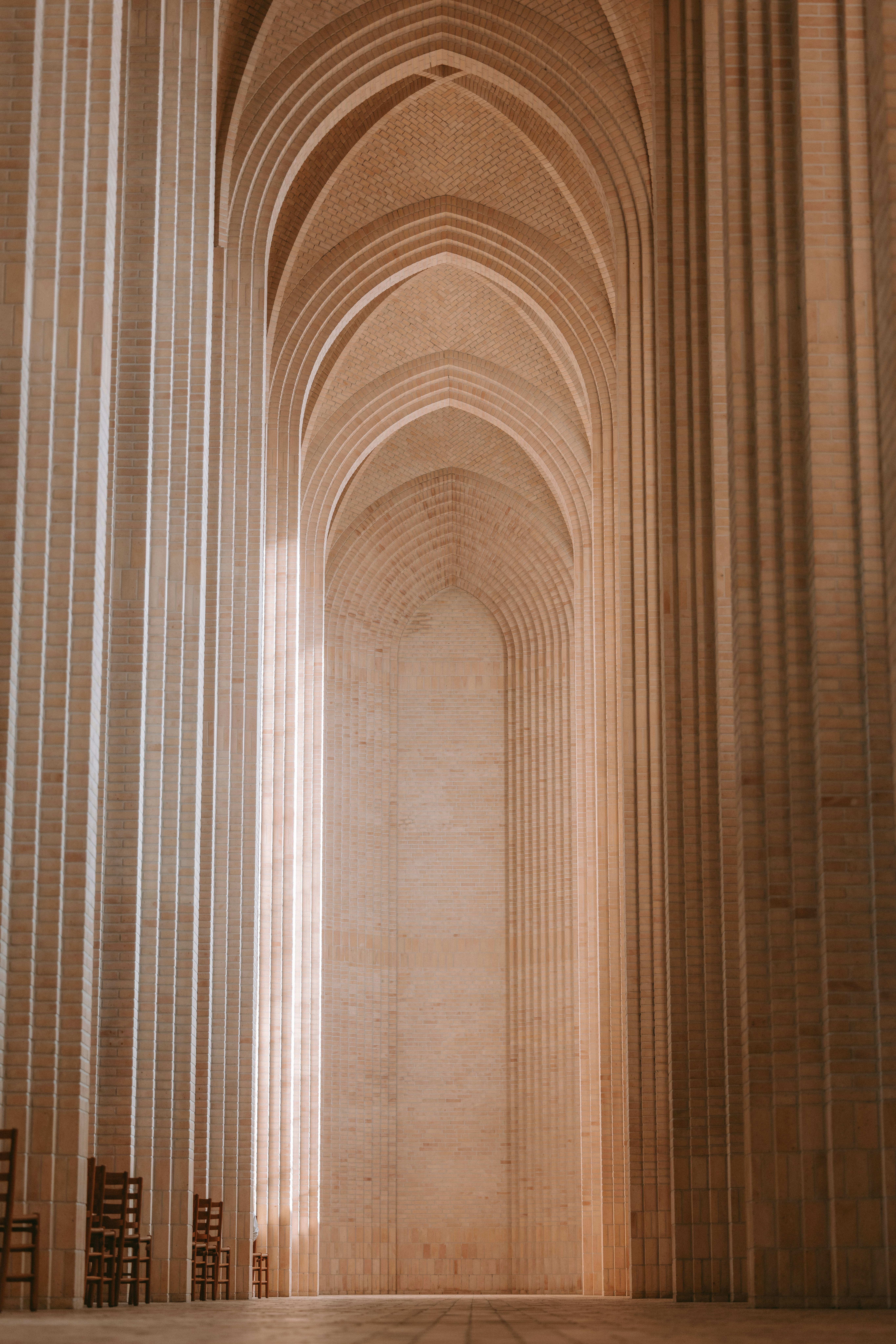 Arched hall with rows of columns and chairs.