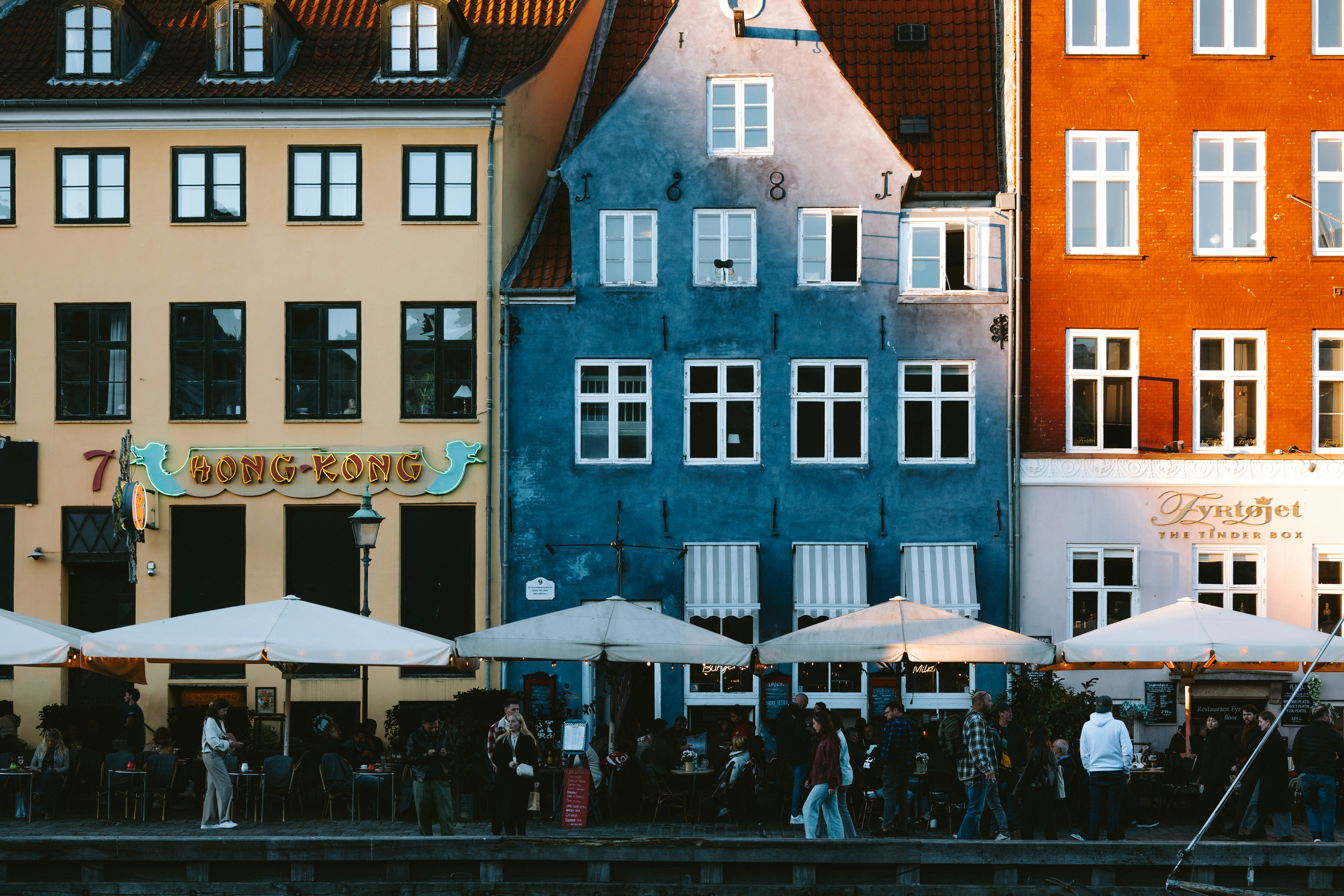 Colorful buildings line a waterfront with outdoor seating.