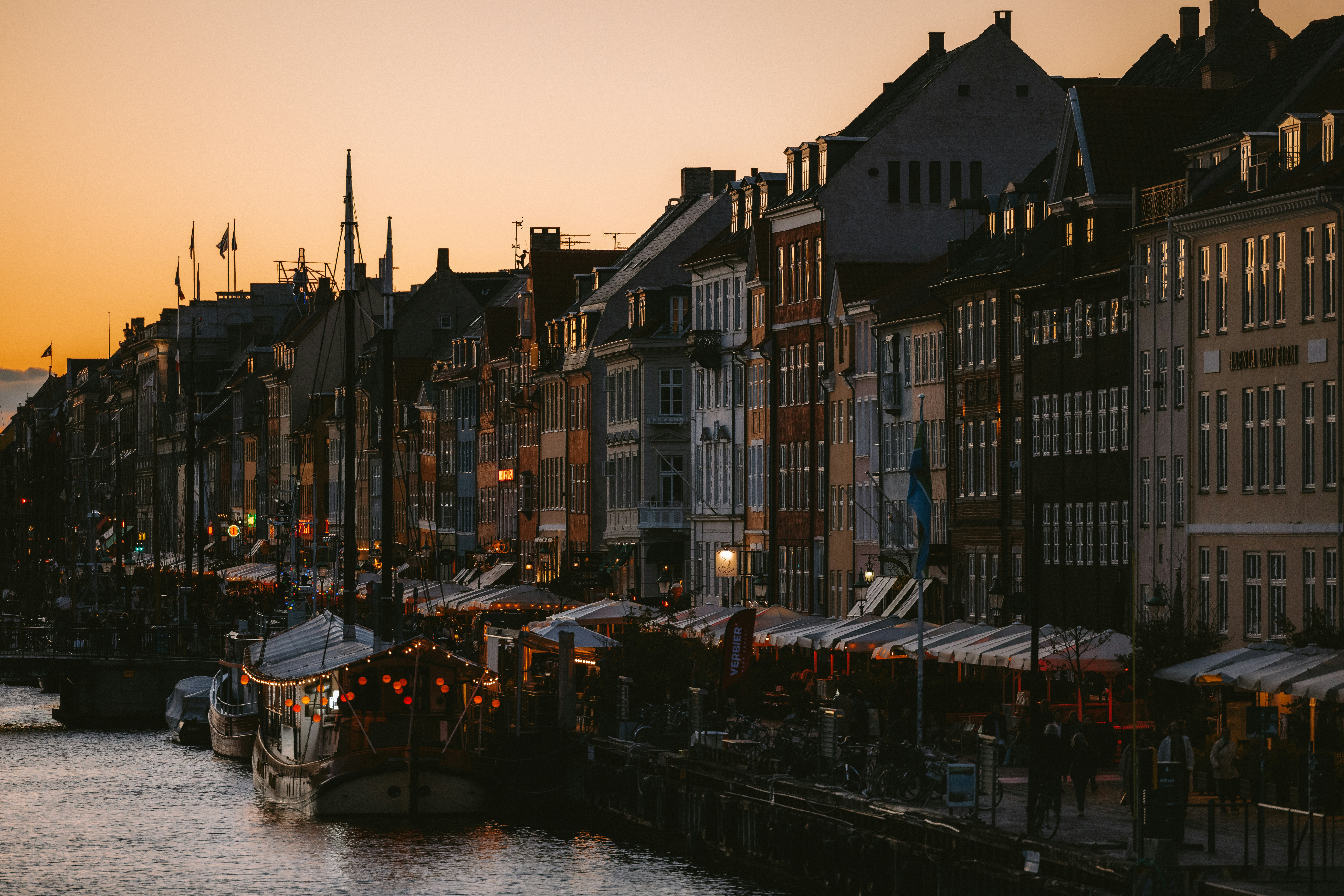 Waterfront buildings with outdoor seating at dusk.
