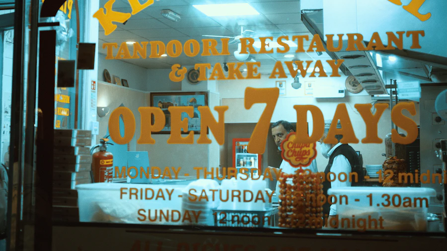 A tandoori restaurant front at night, lit sign in the window reading open seven days