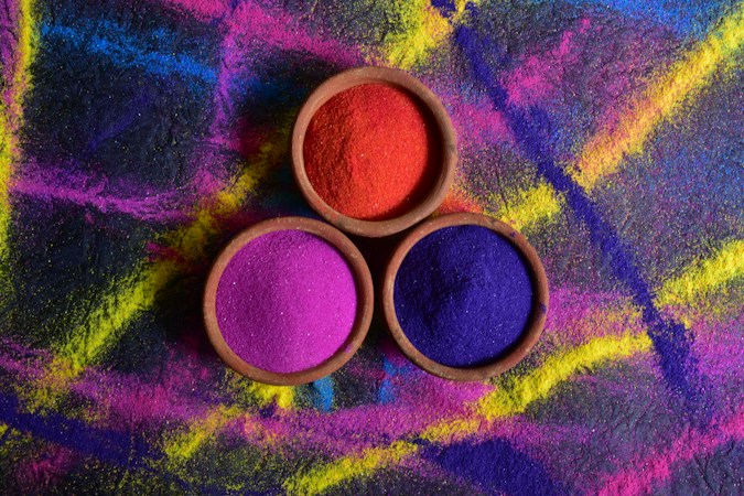 Bowls of brightly colored powder in red, yellow, blue and green