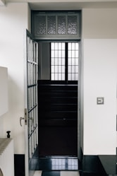 Open door reveals dark staircase with window