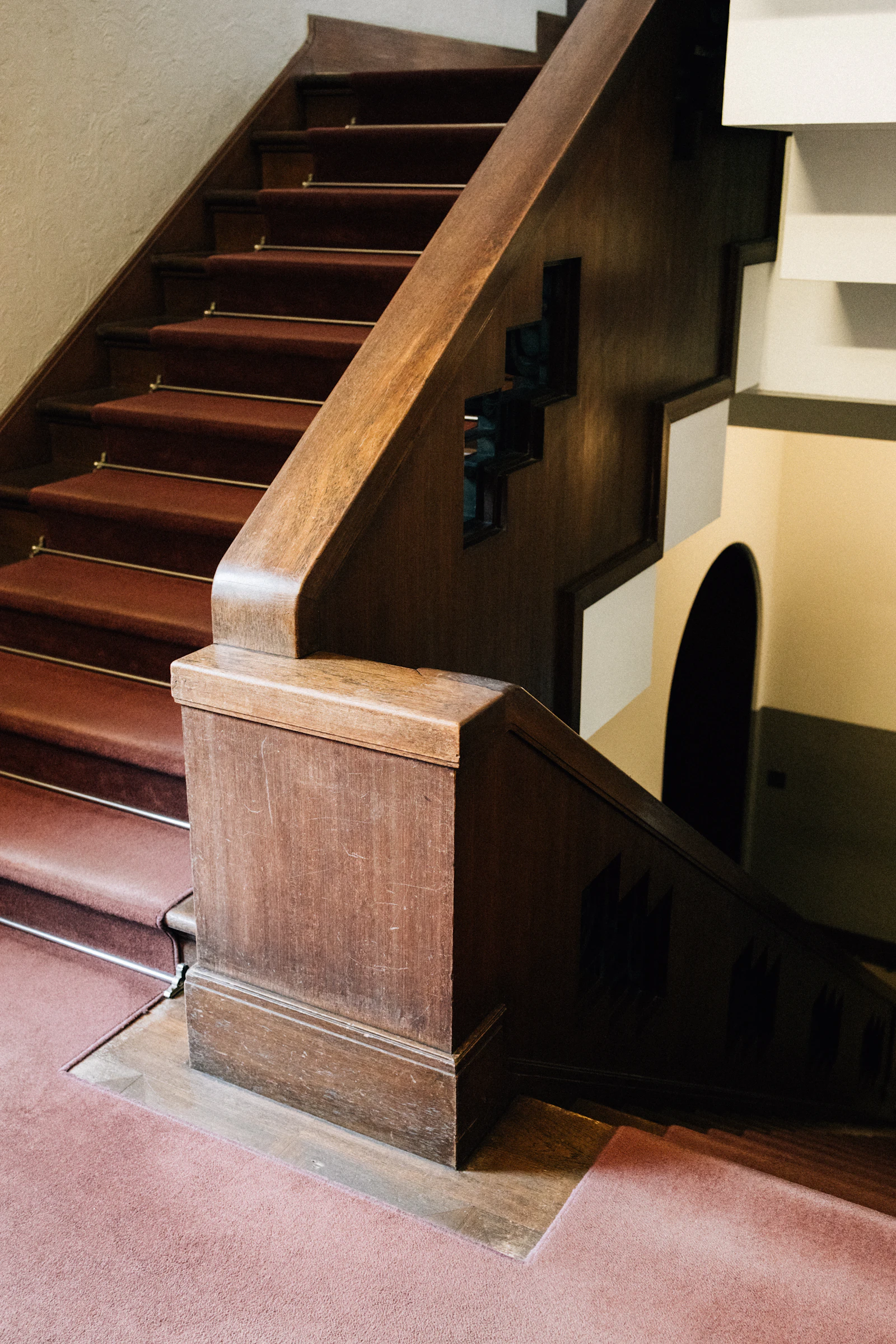 Wooden staircase with red carpet and ornate railing