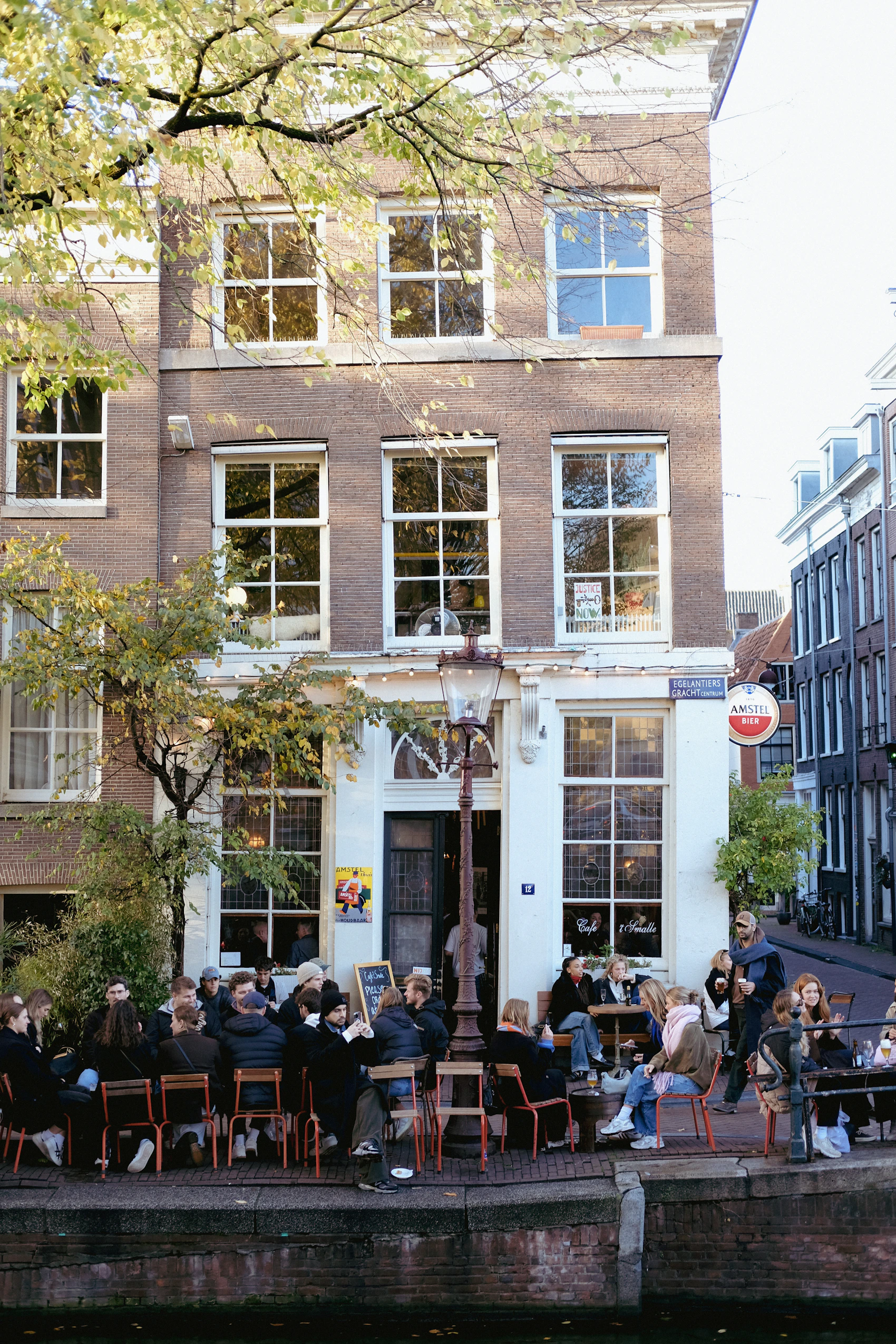 Friends dining at an outdoor café terrace beside an Amsterdam canal