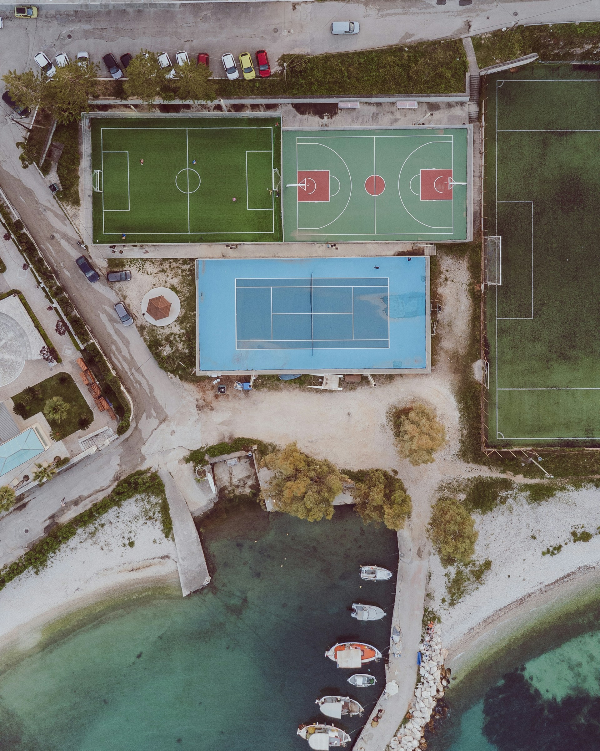 Aerial view of sports courts and boats by the sea