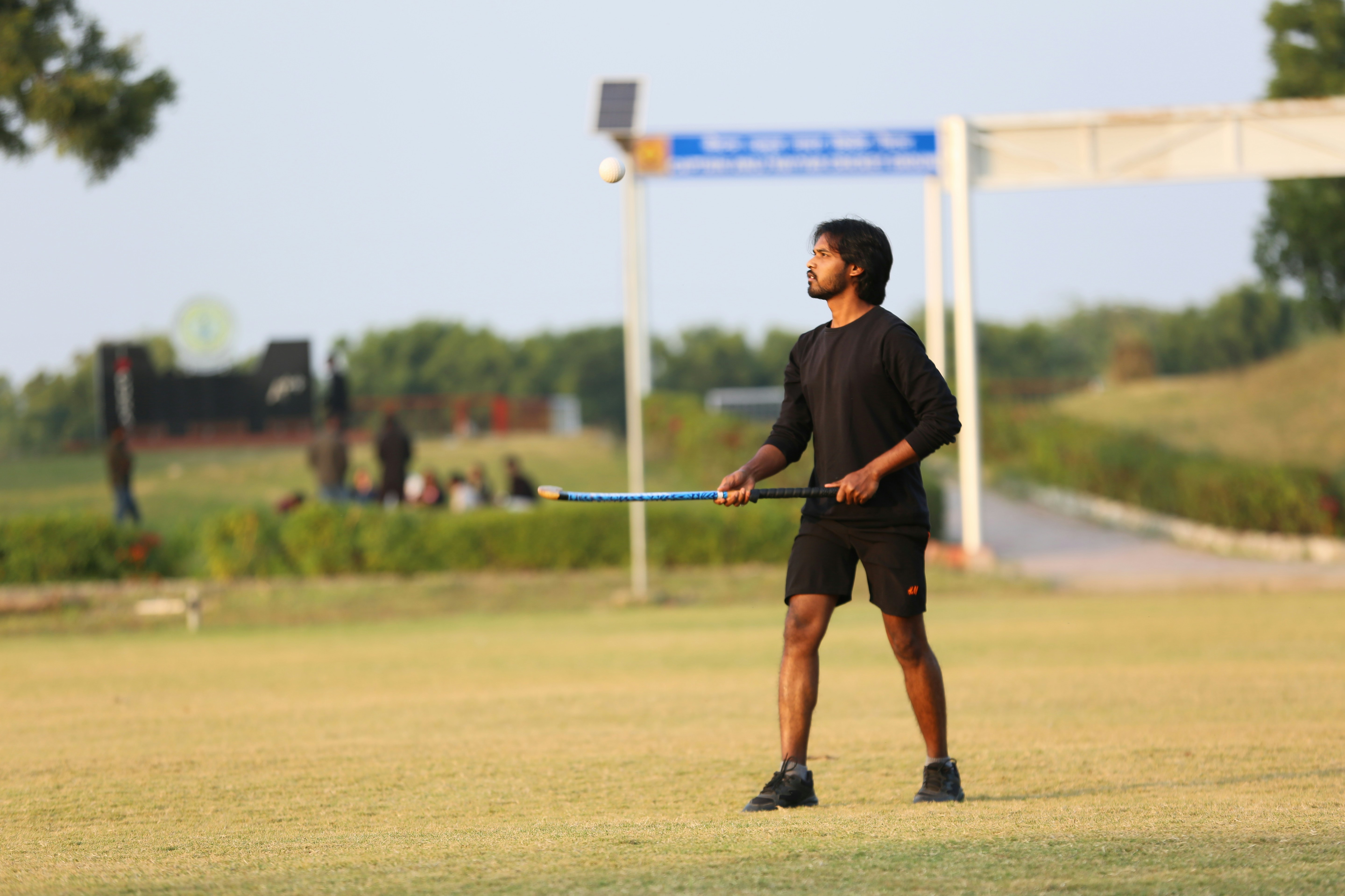 Young man holding a hockey stick on grassy field