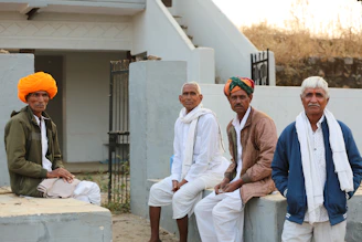 Four men in traditional indian attire sitting outside.