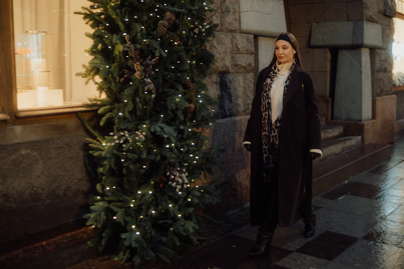 mujer pasa junto a un árbol de Navidad de noche
