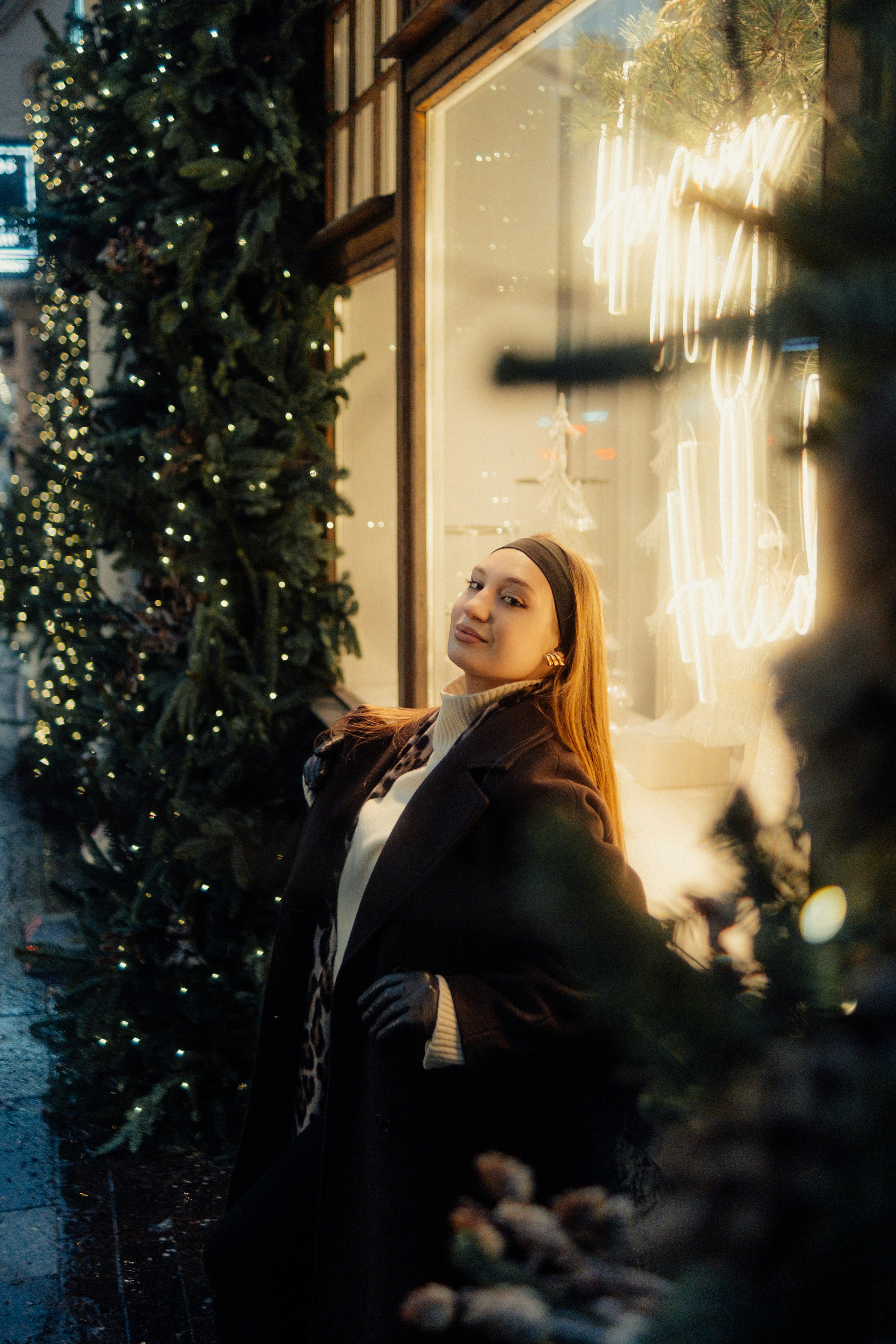 Young woman posing near a christmas tree with lights