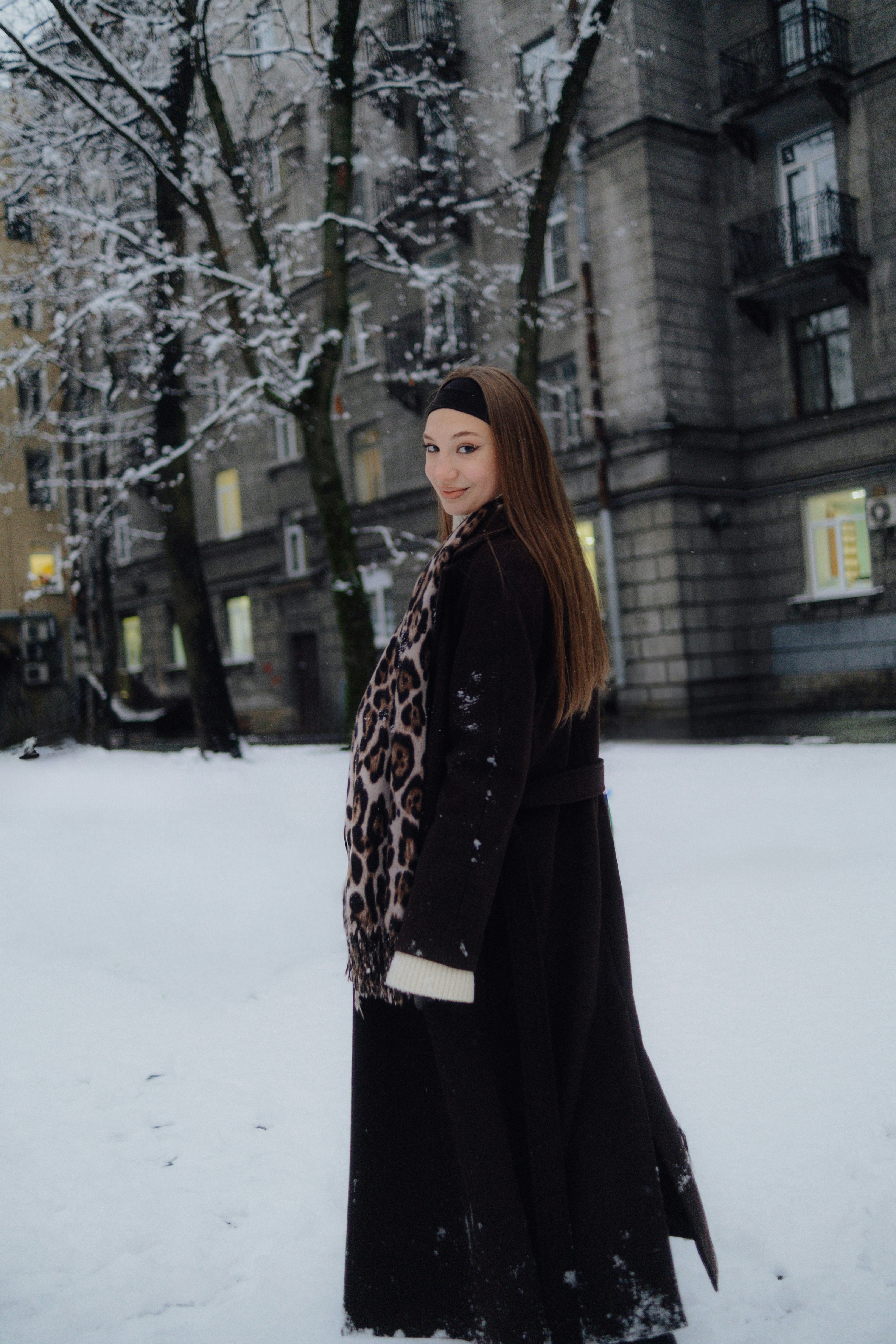 Woman in coat standing in snowy courtyard