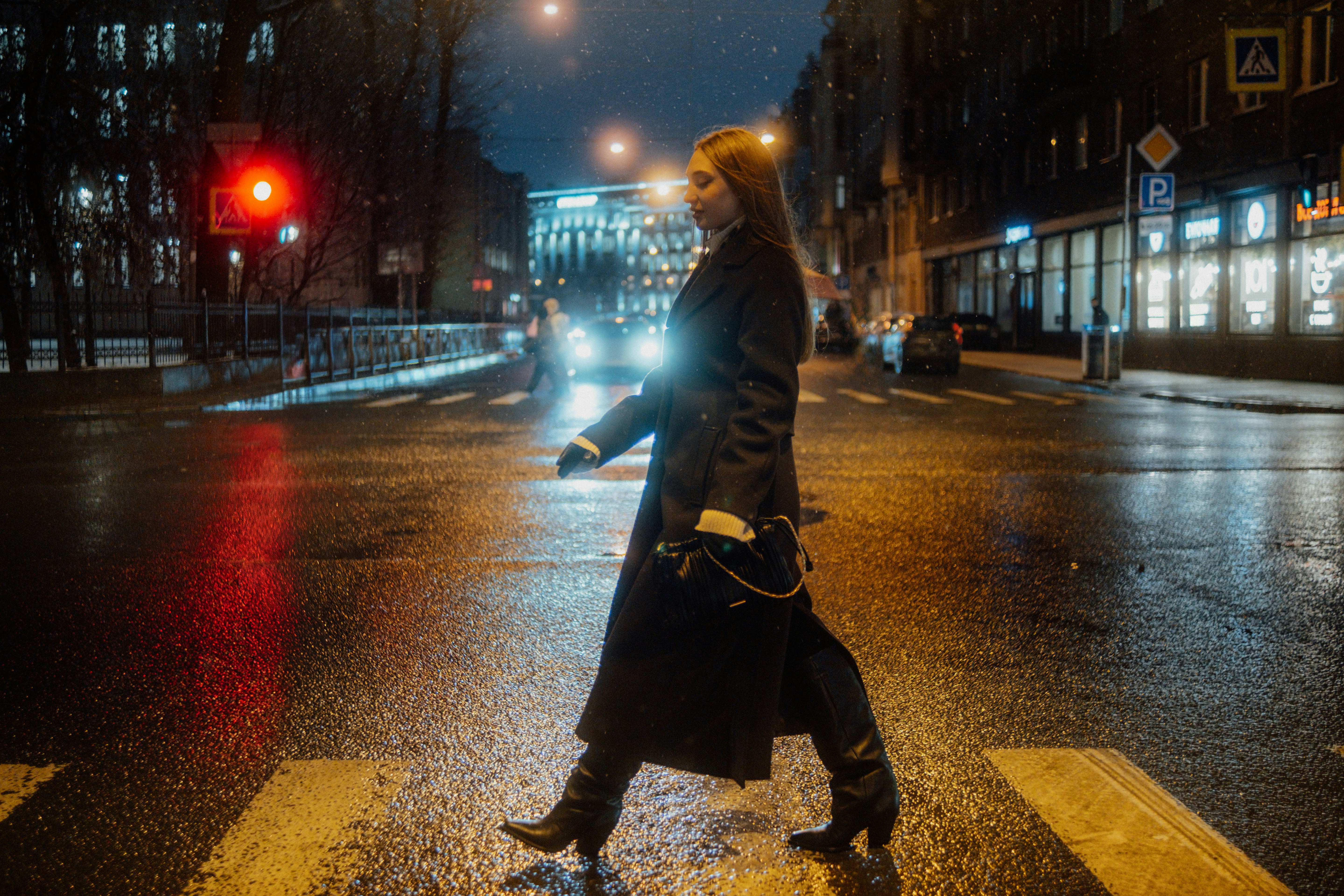 Woman crosses wet street at night