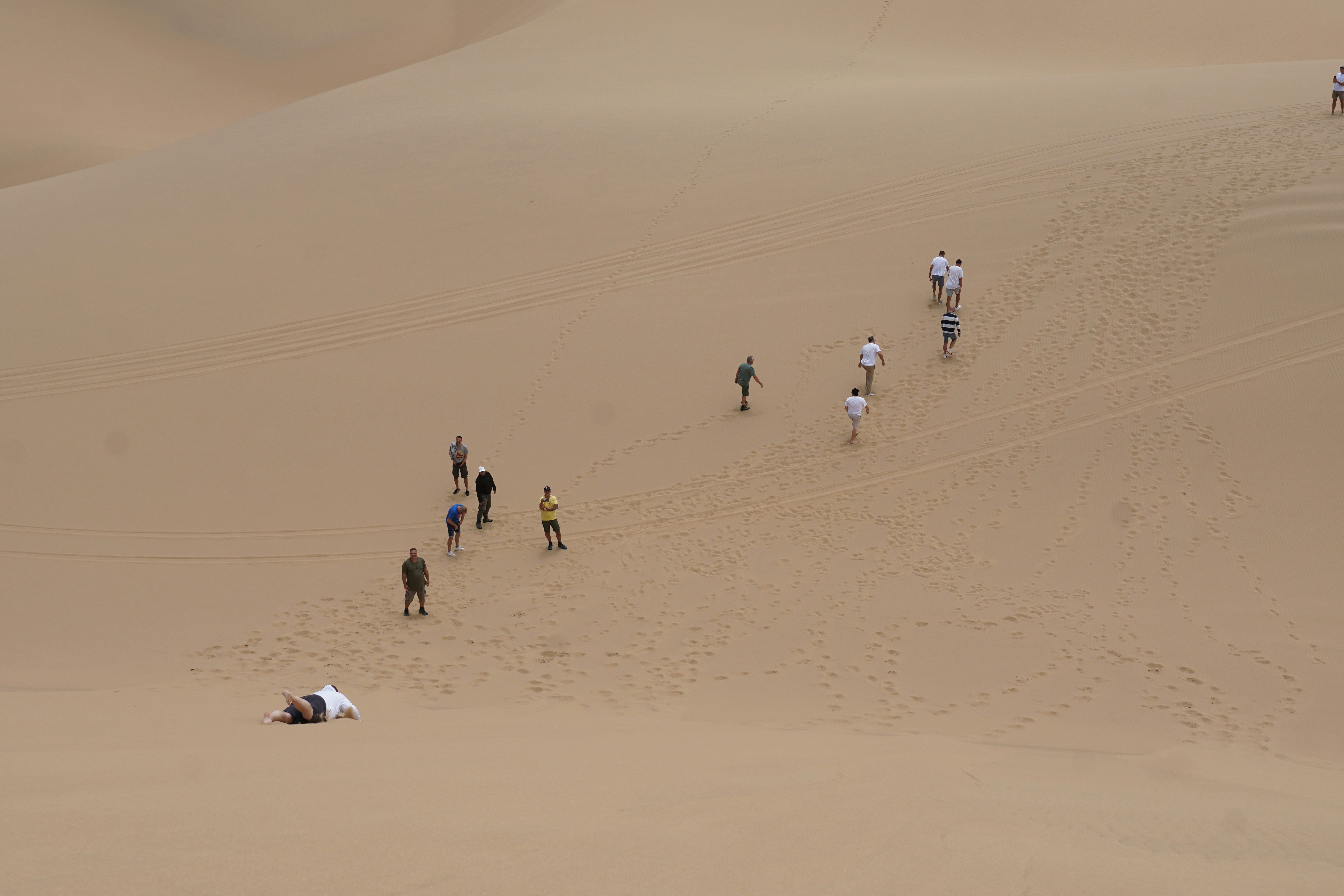 People walking up a large sand dune