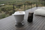Bathtub on a wooden deck overlooking savanna landscape.