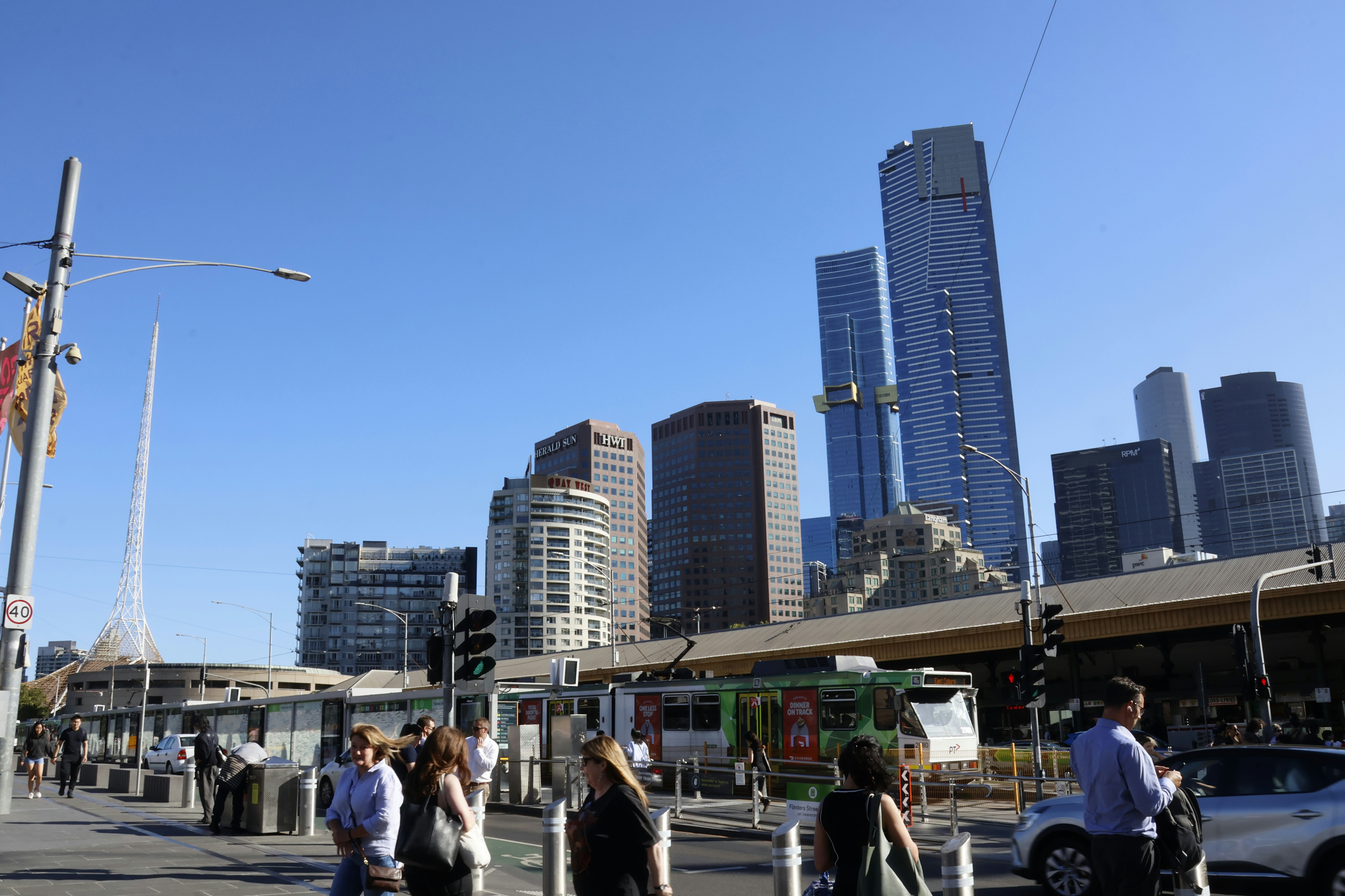 People walking on street with cityscape and tram.