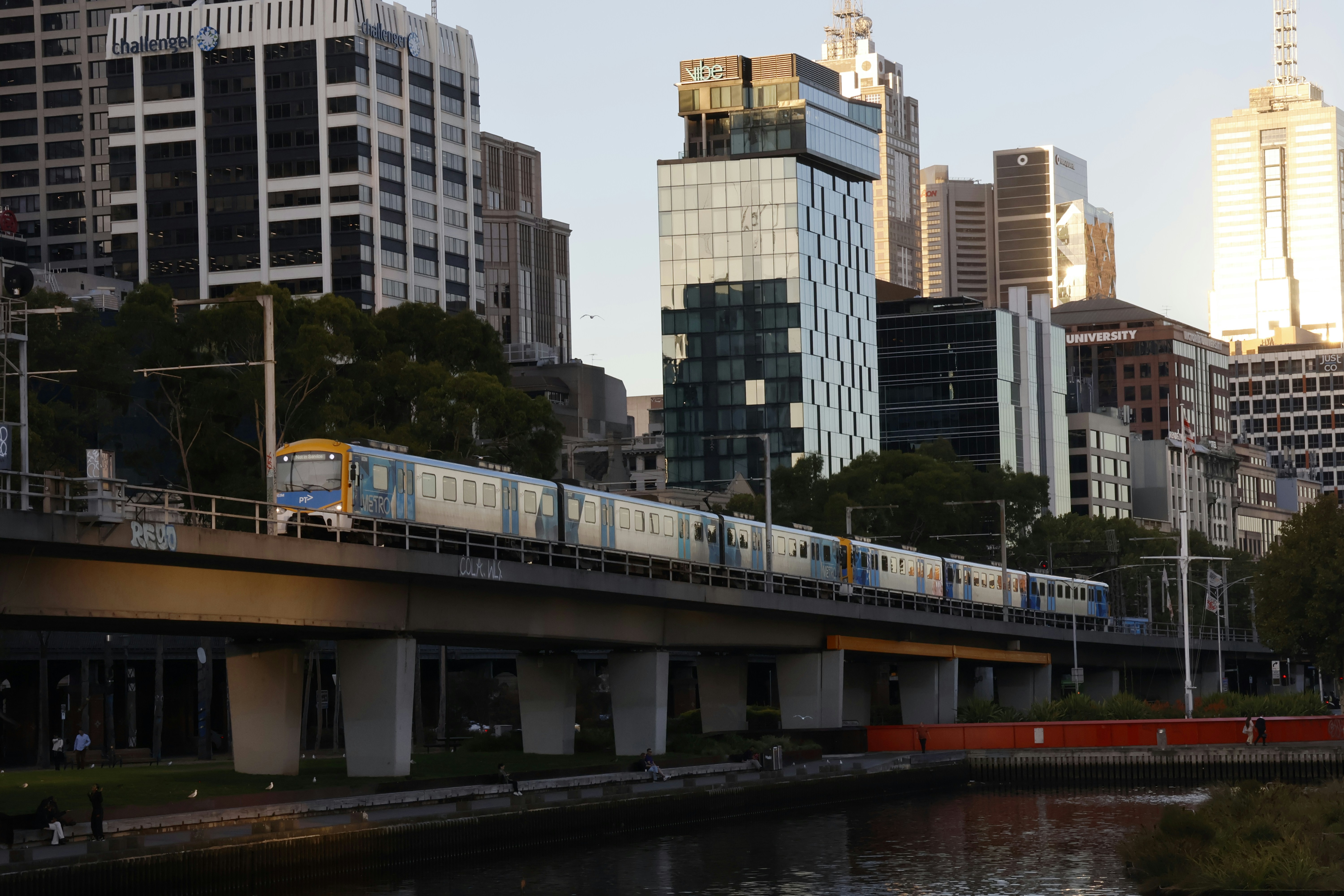 Train crossing a bridge with city buildings behind