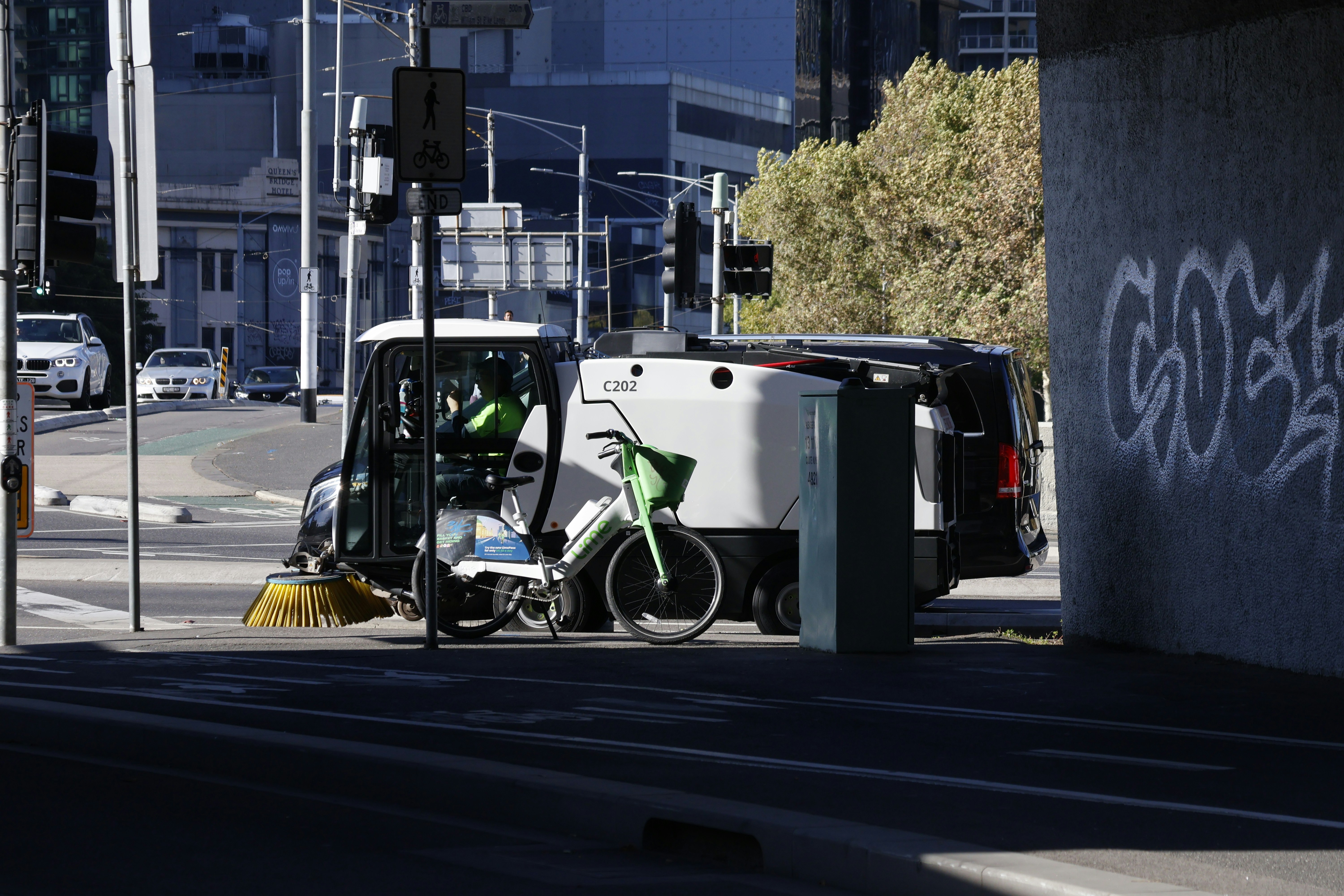Street sweeper parked under a bridge with graffiti