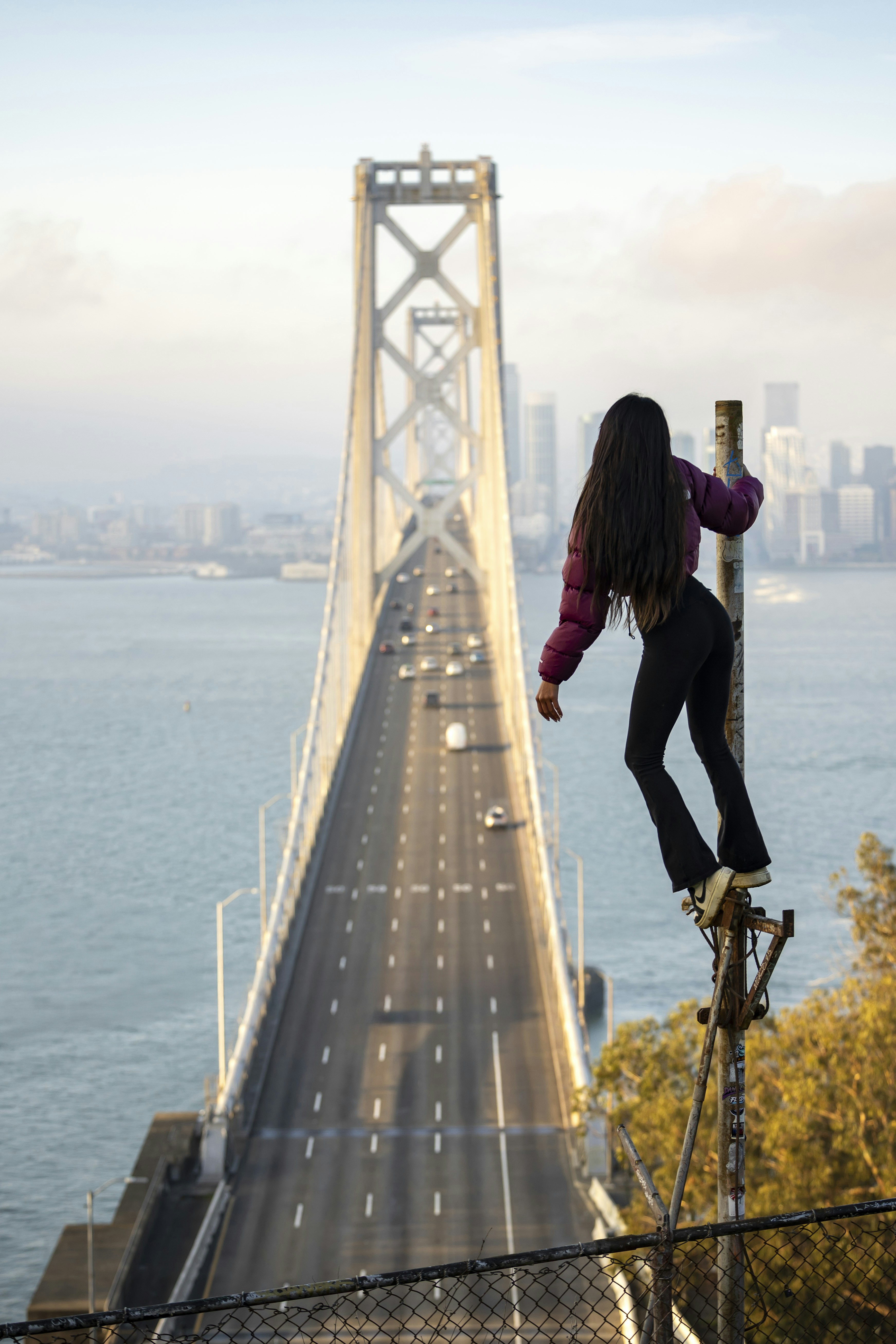 Woman on pole overlooking bridge and city