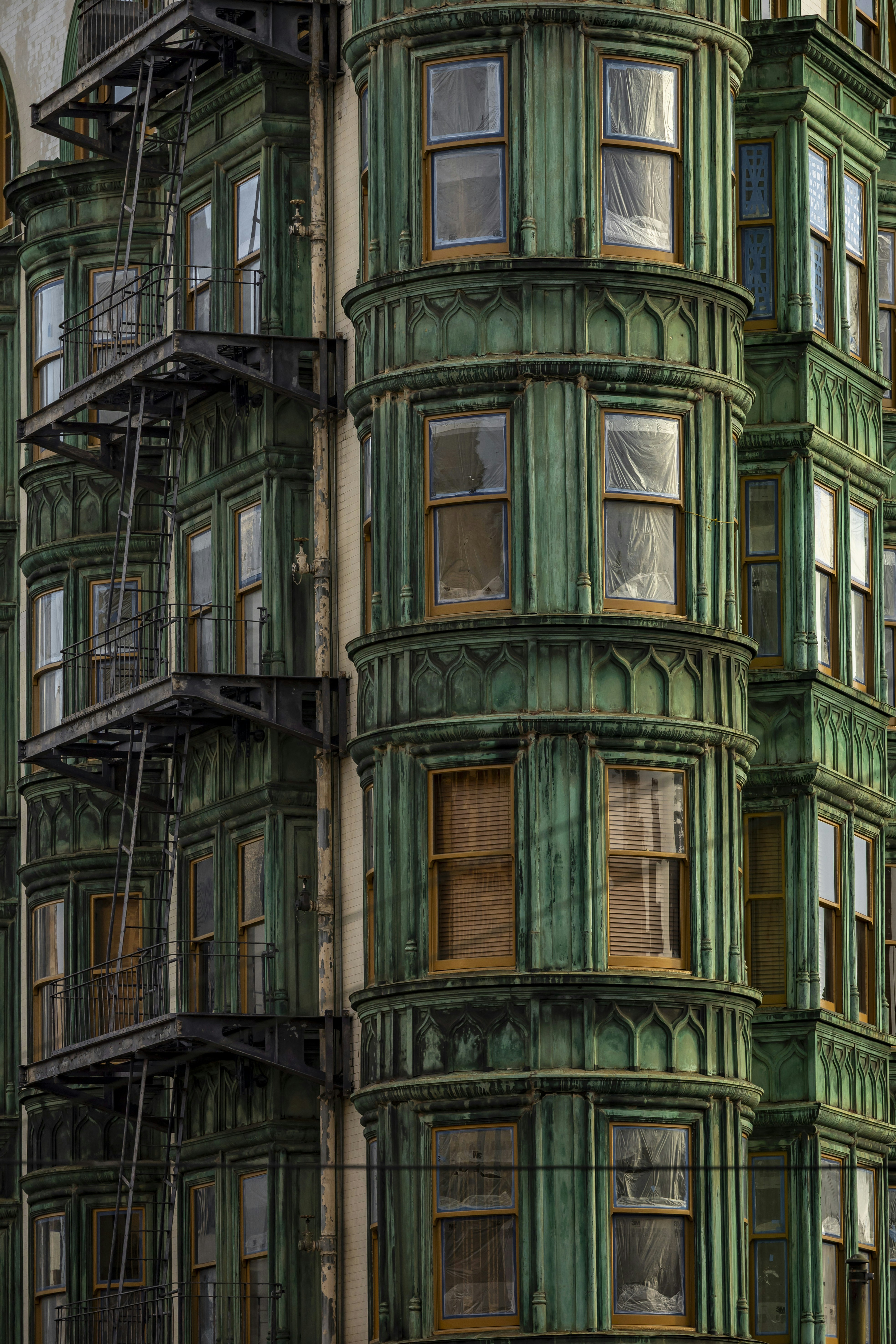 Ornate green building with bay windows and fire escape