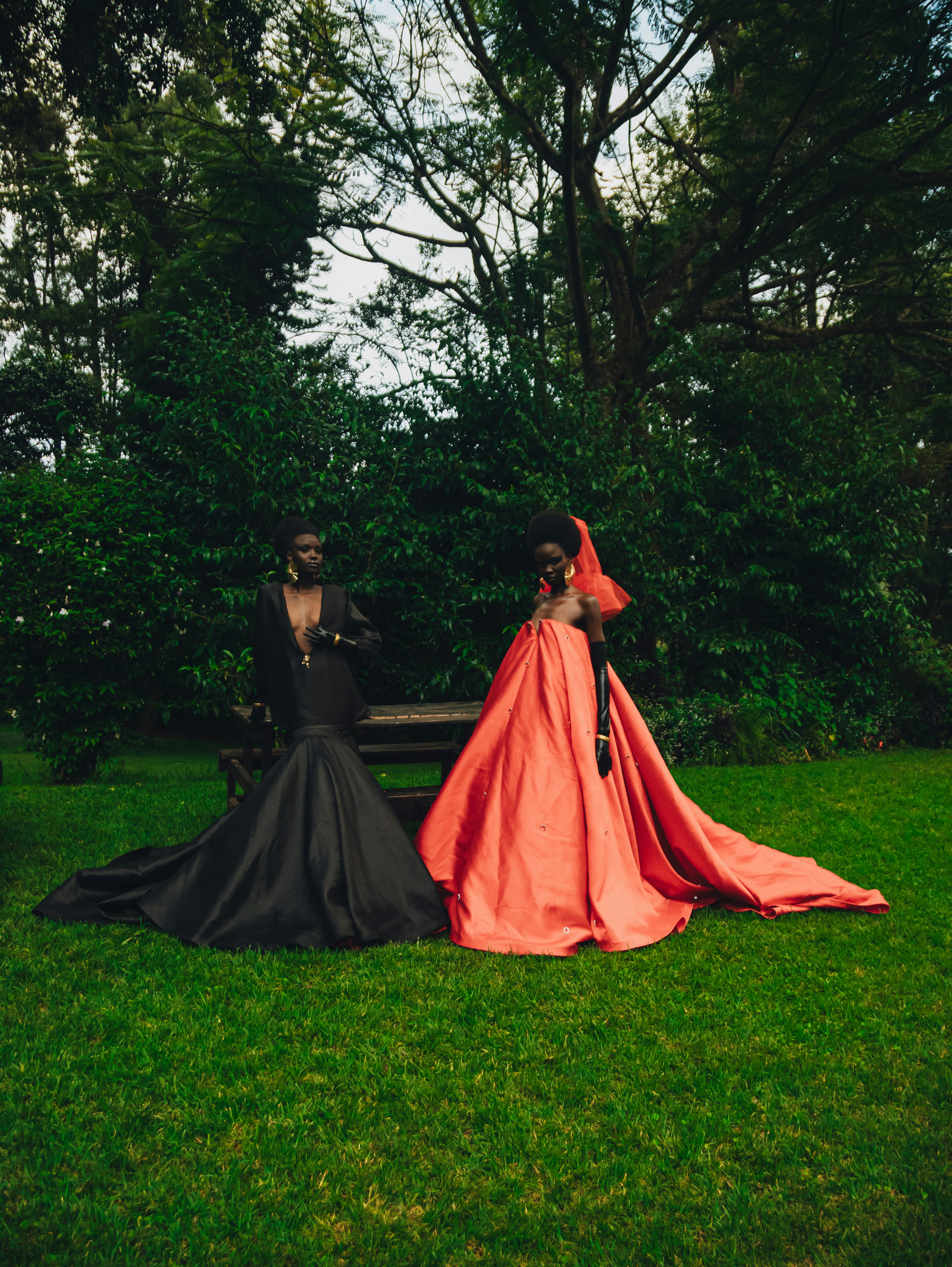 Two people in elaborate gowns on grassy lawn
