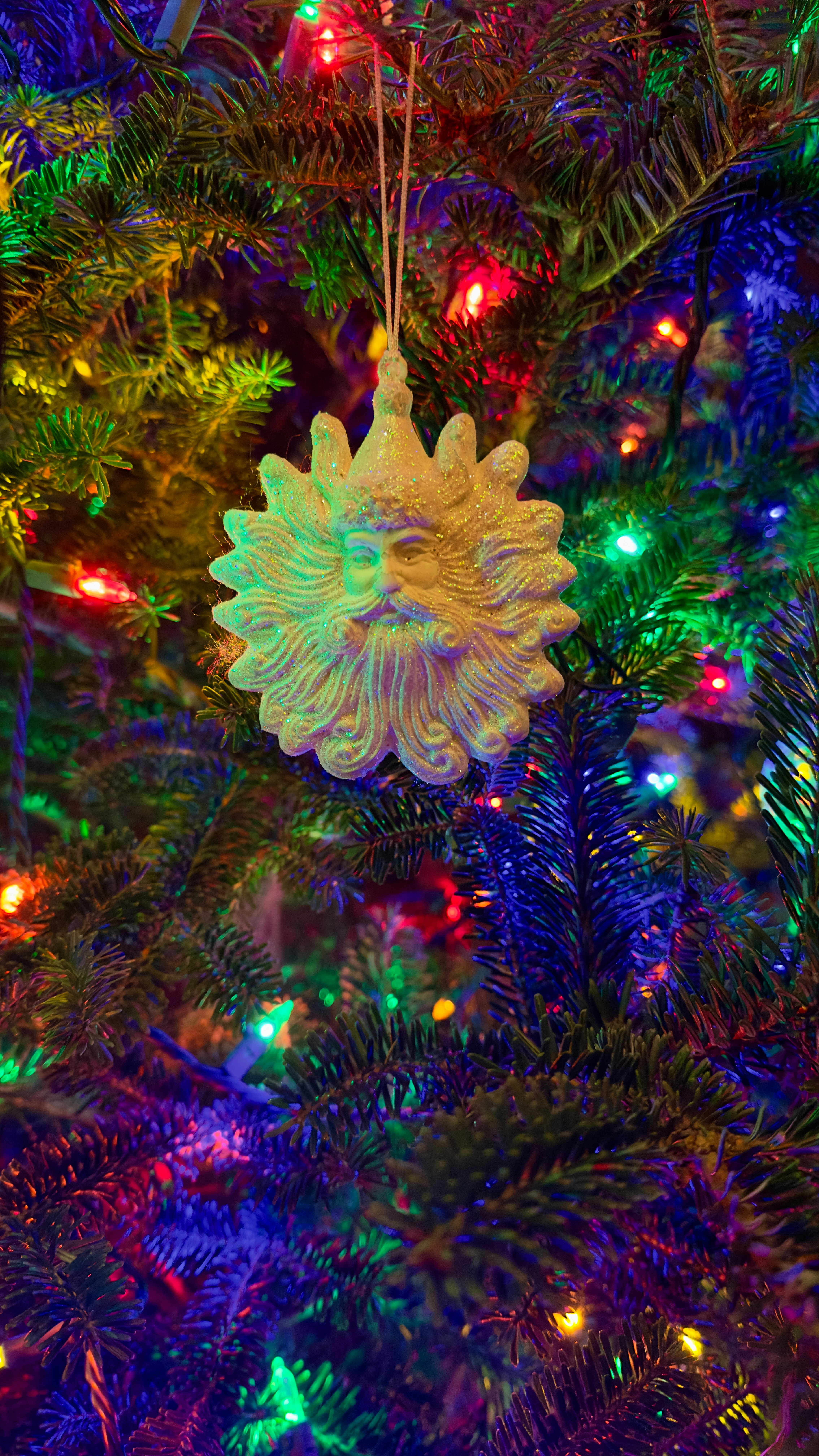 Sun ornament on a christmas tree with lights.