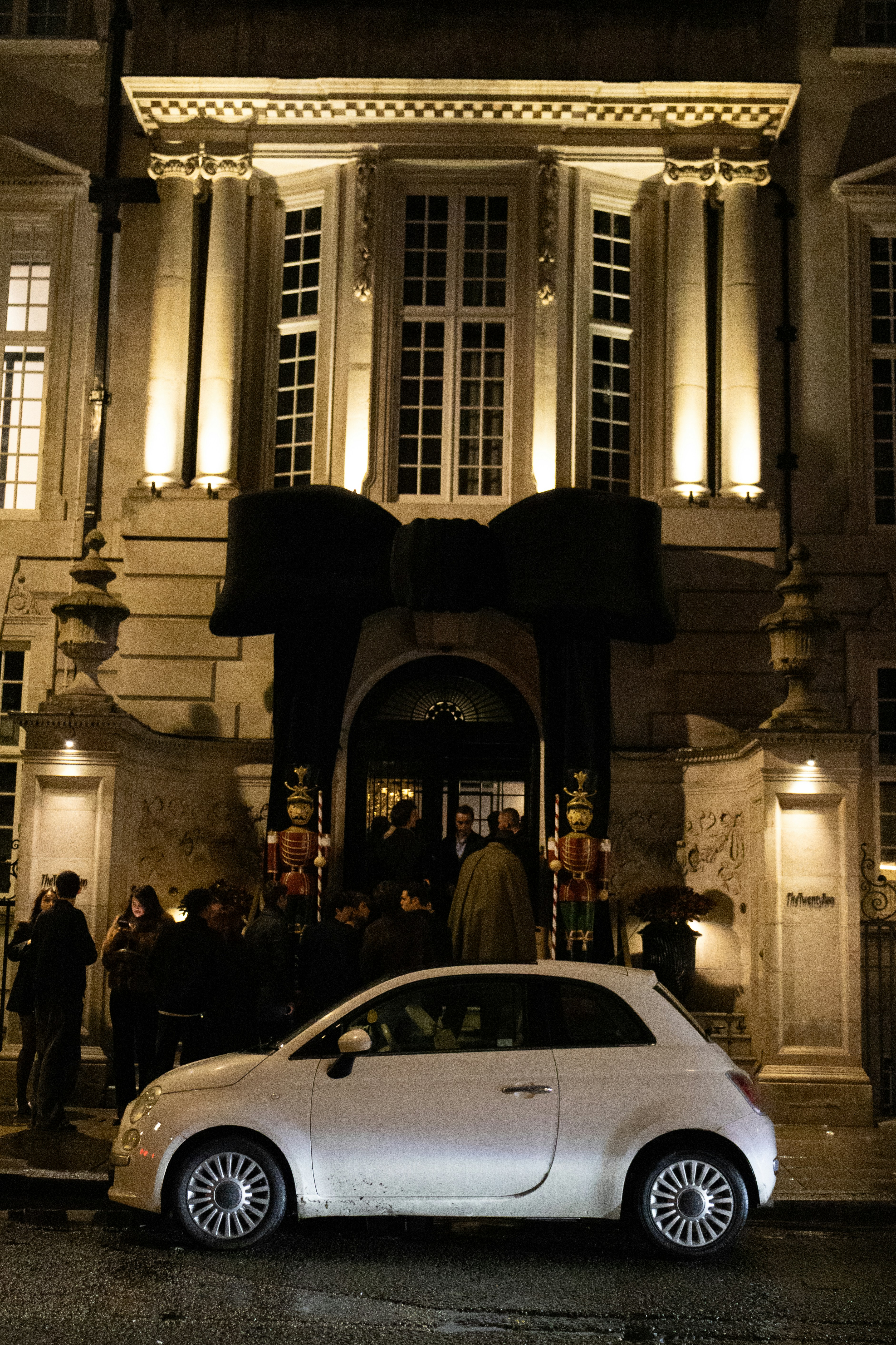 White car parked outside building with large bow entrance