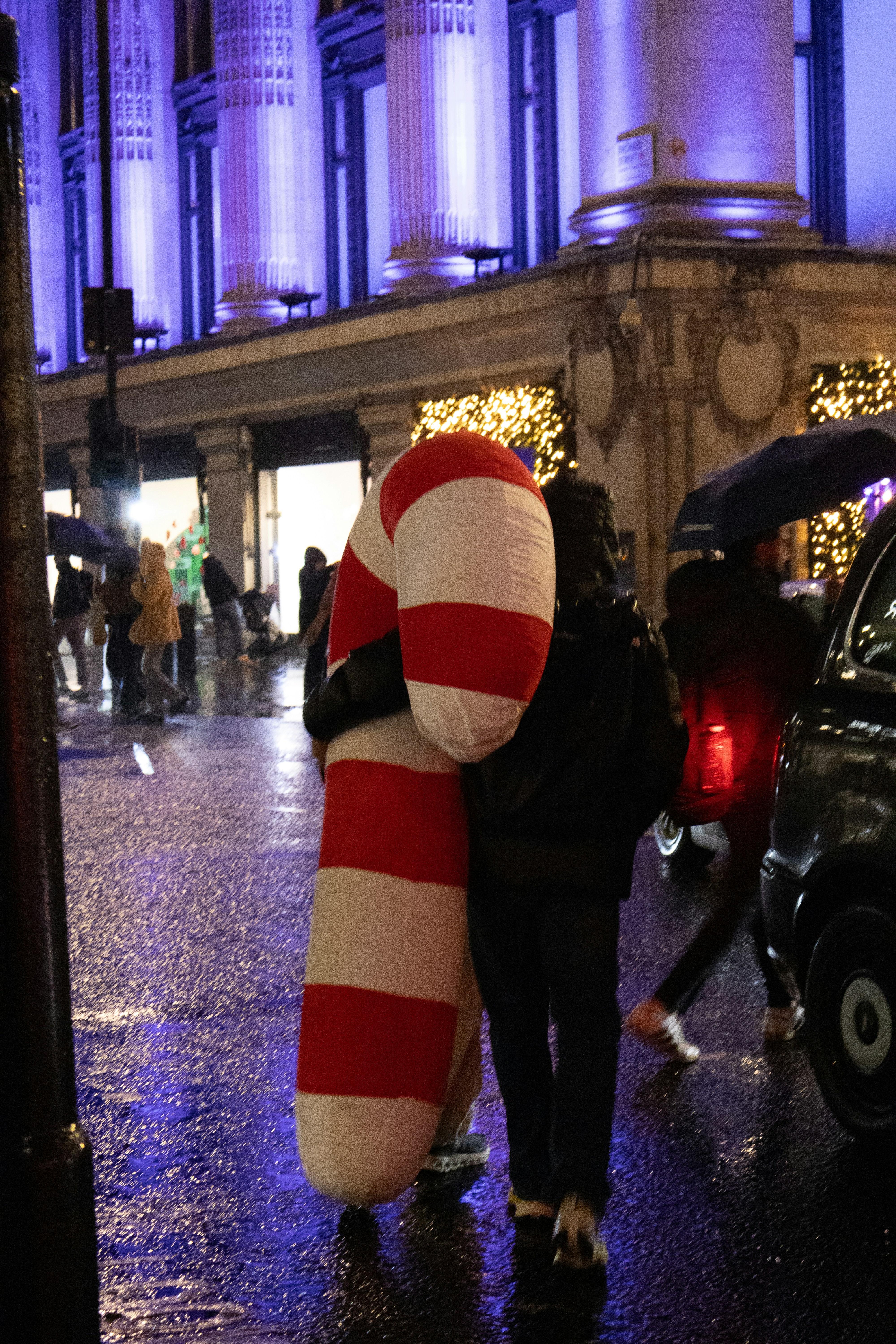 People in costume hug on a wet street at night.