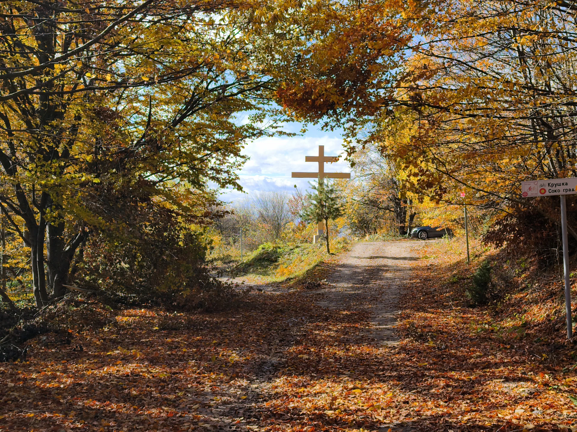 Autumn path leads to a double-barred cross.