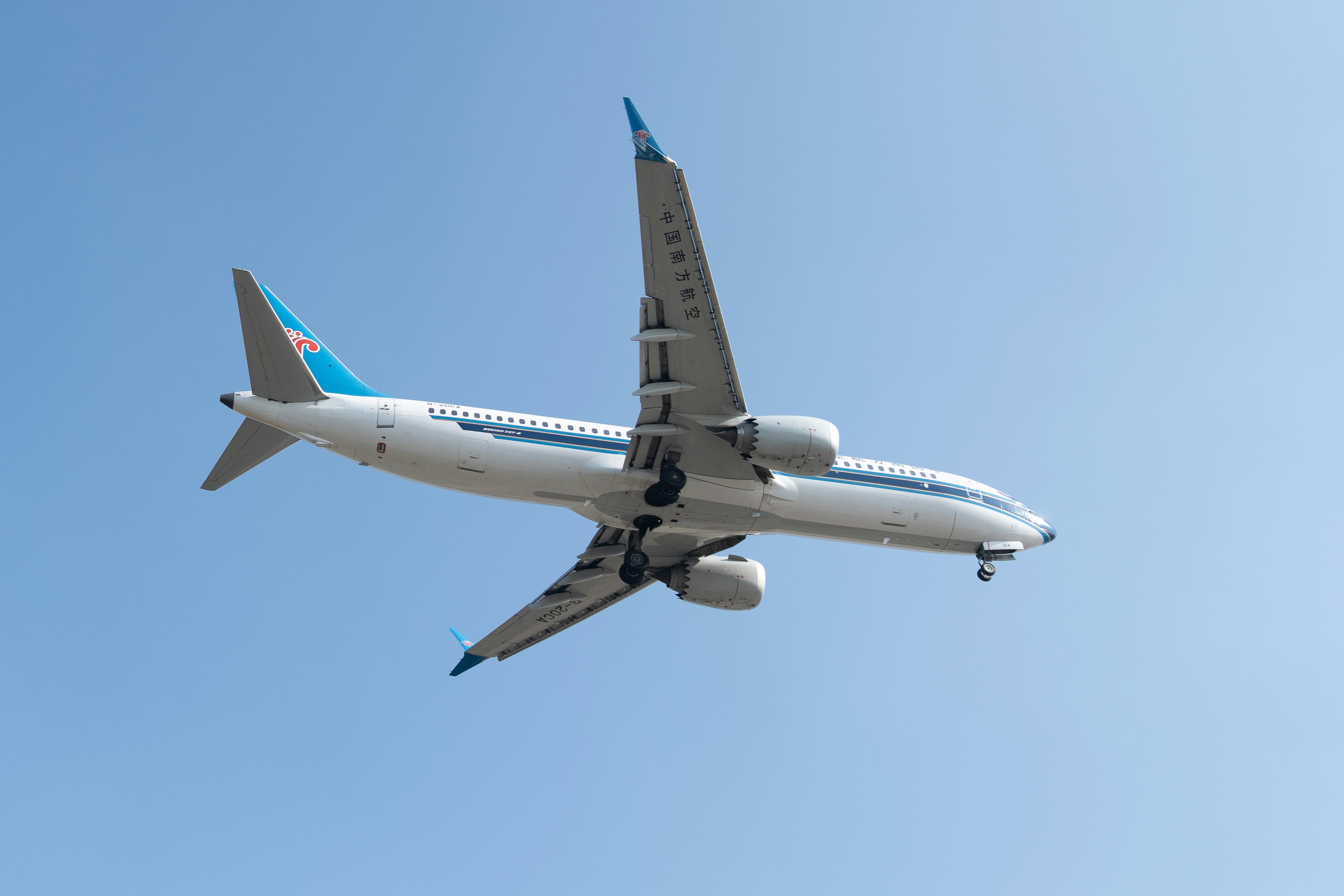 A white airplane flying in a clear blue sky.