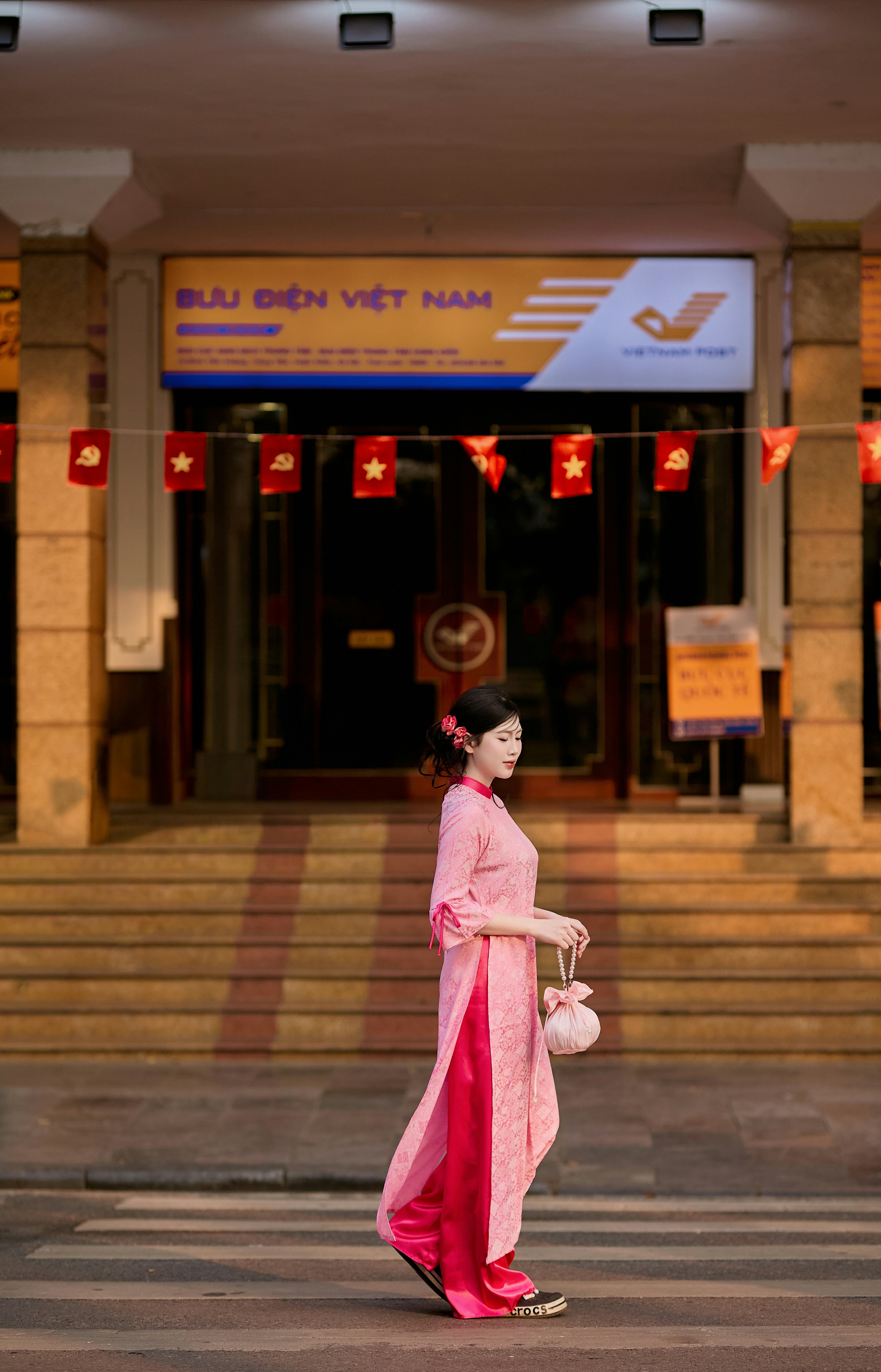 Woman in pink traditional dress walks on street.