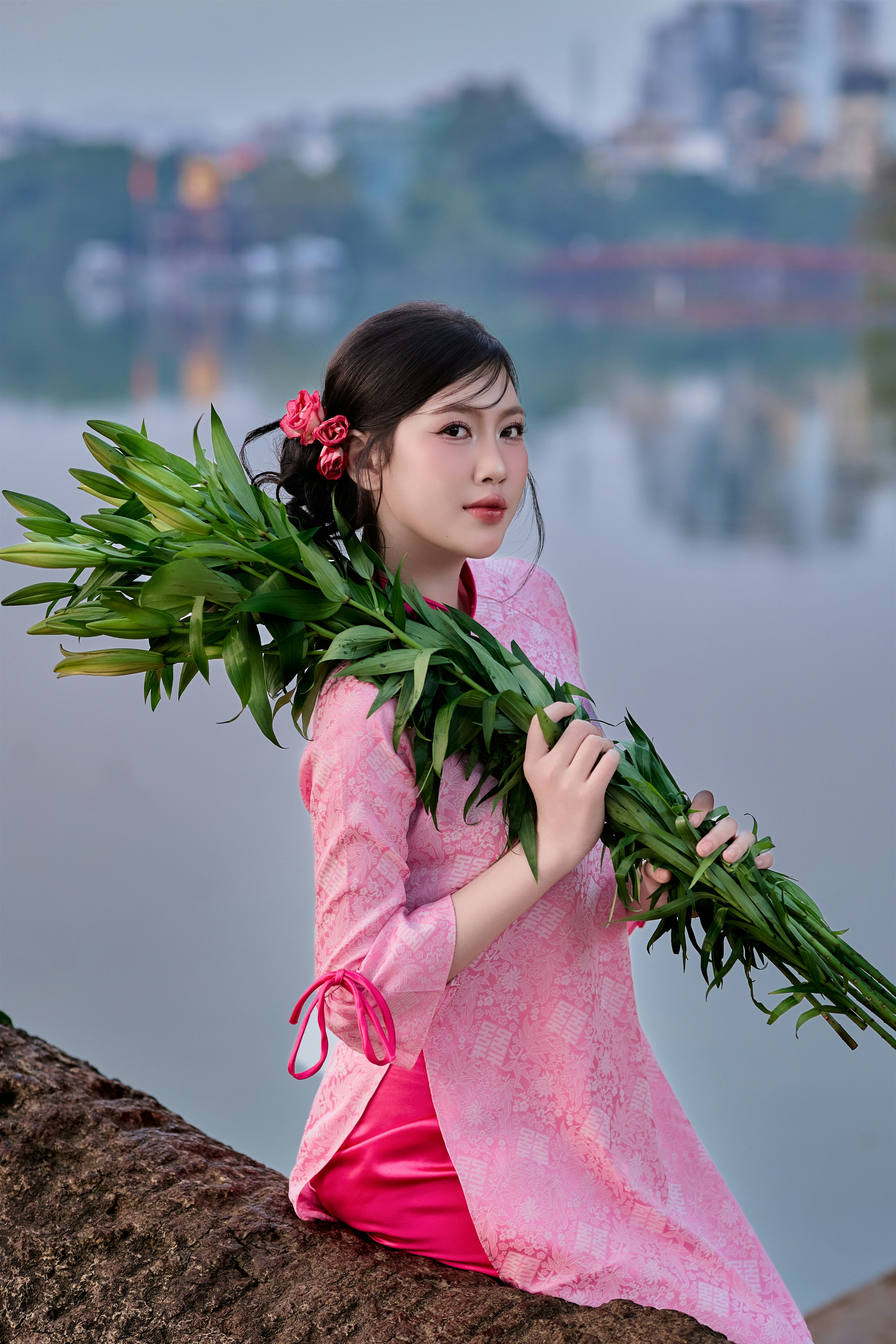 Young woman in pink dress holding green branches