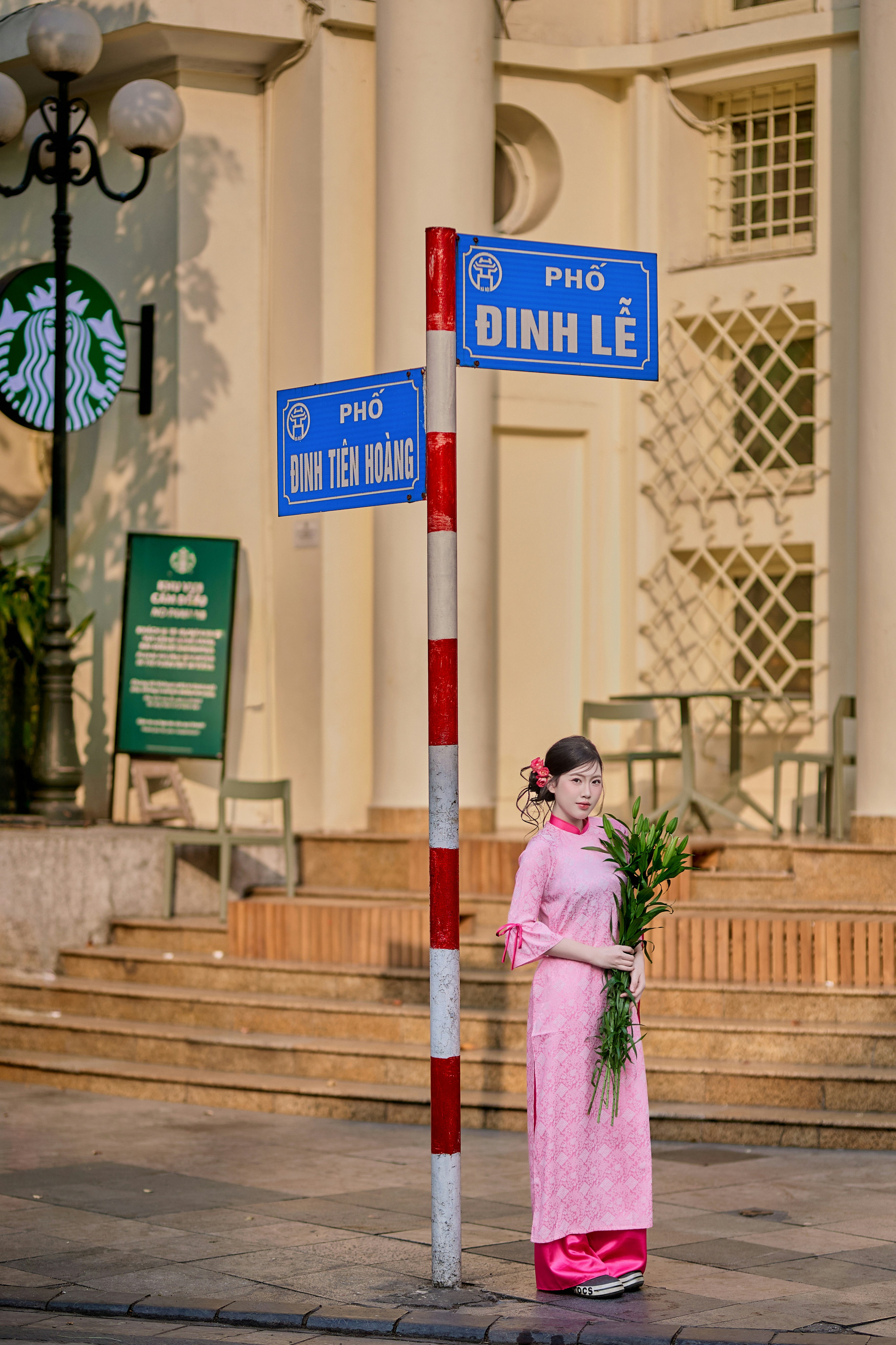 Woman in pink dress holding flowers by street sign