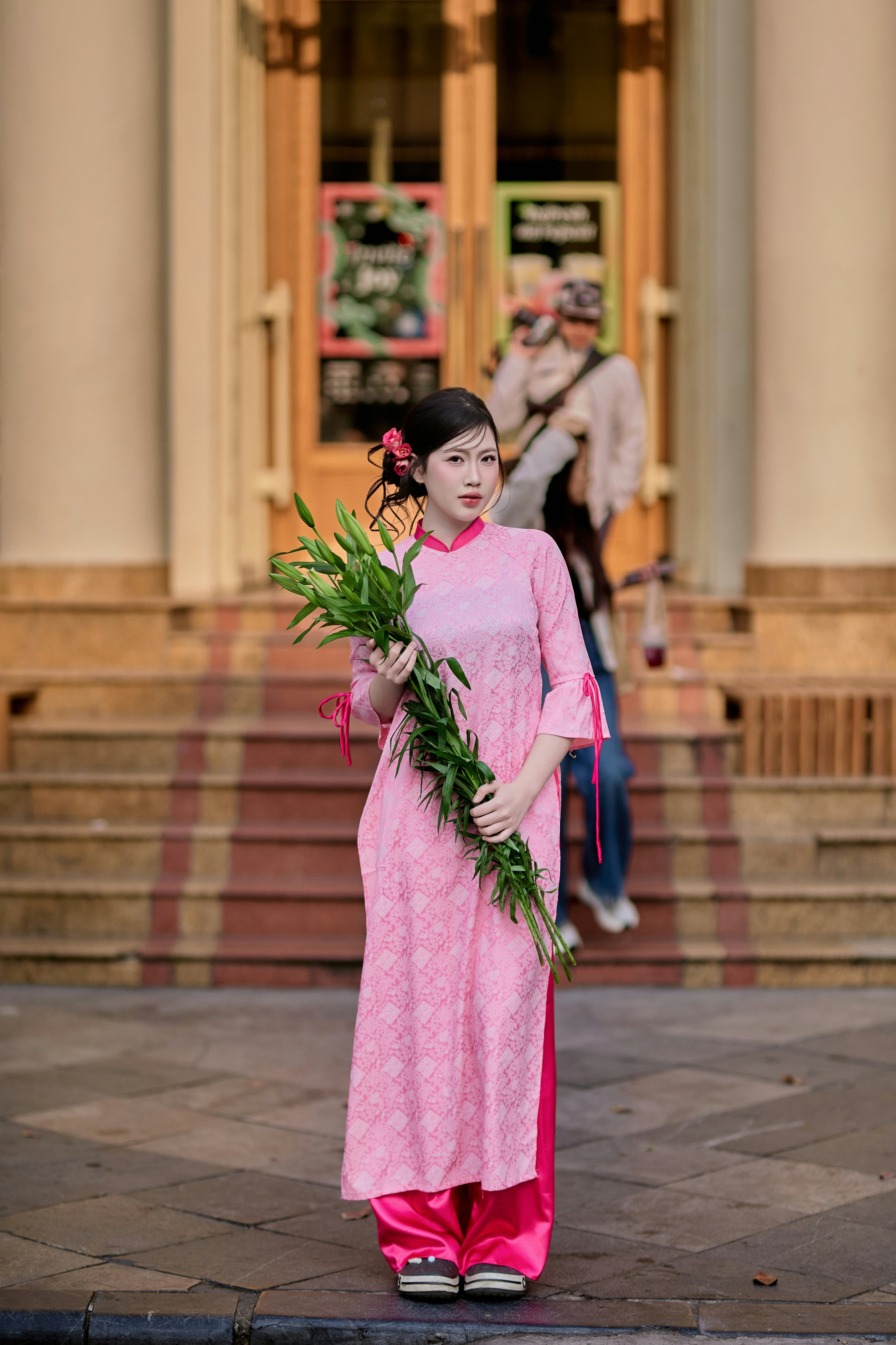 Young woman in pink dress holding lilies