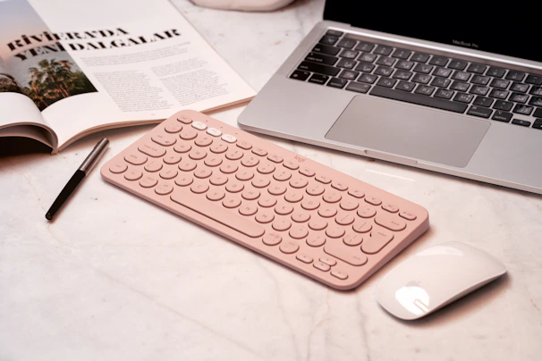 Pink keyboard, mouse, and laptop on a desk