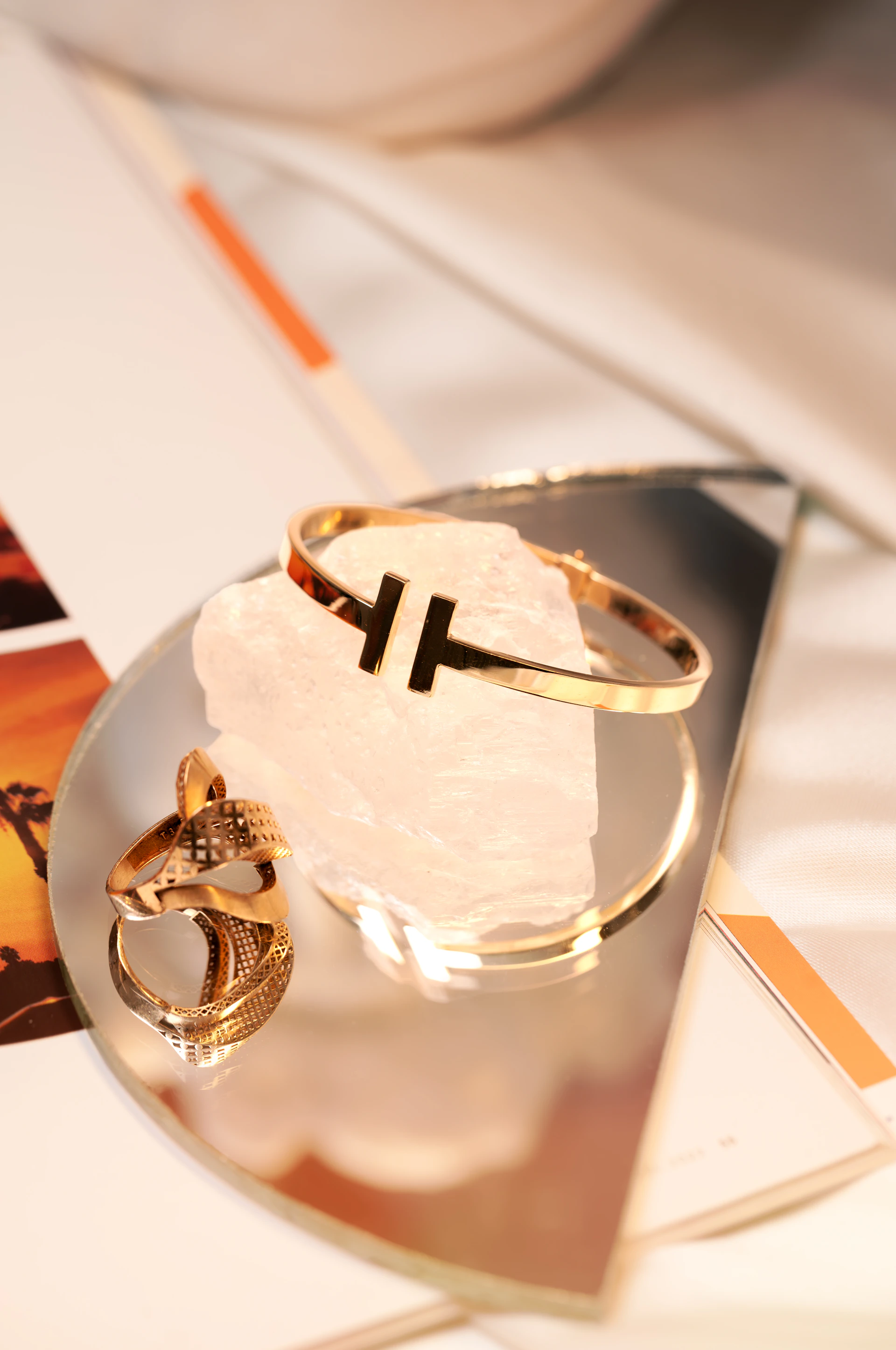 Gold bracelet and ring on reflective surface