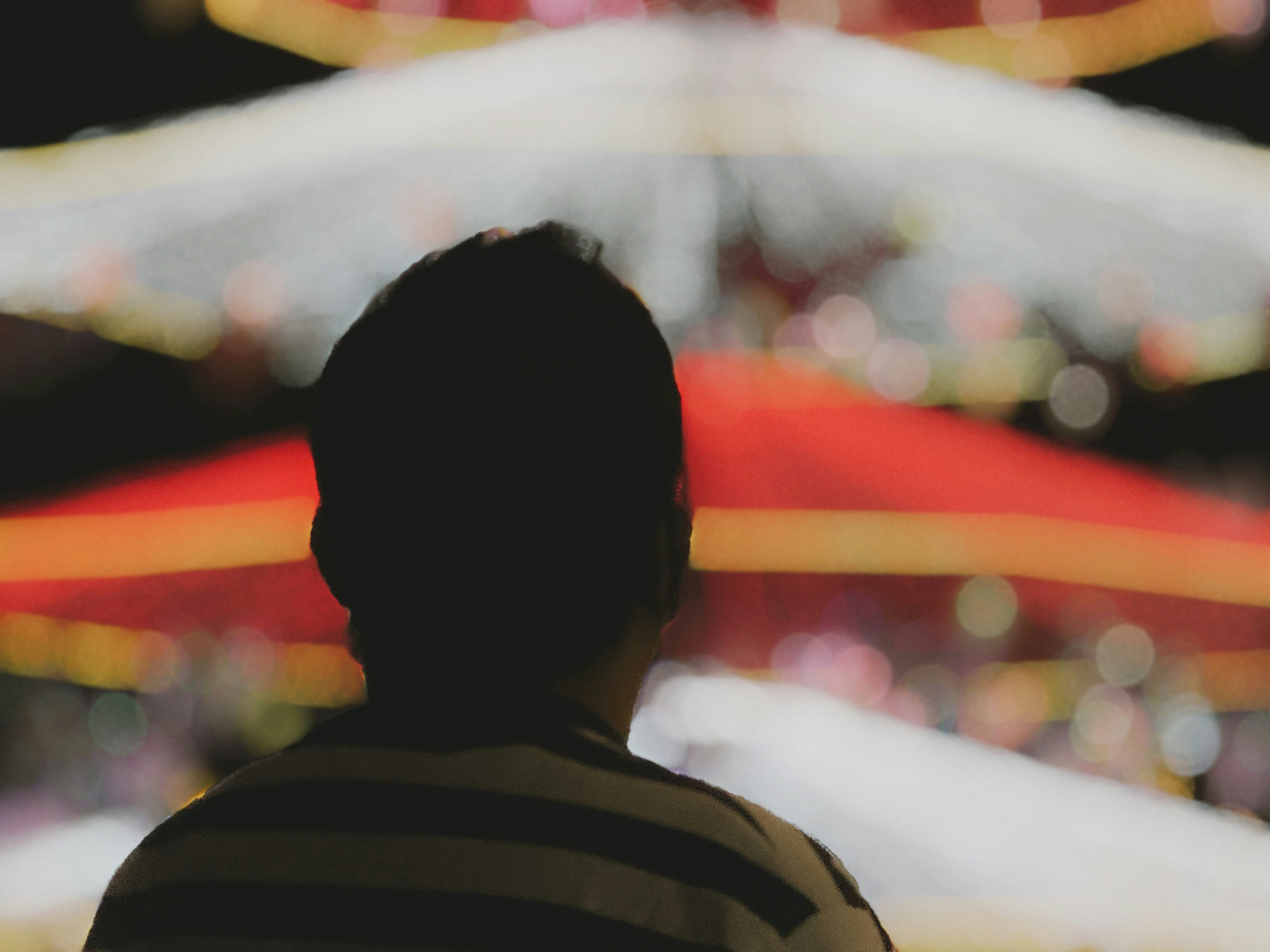 Person looking at colorful blurred lights at night.