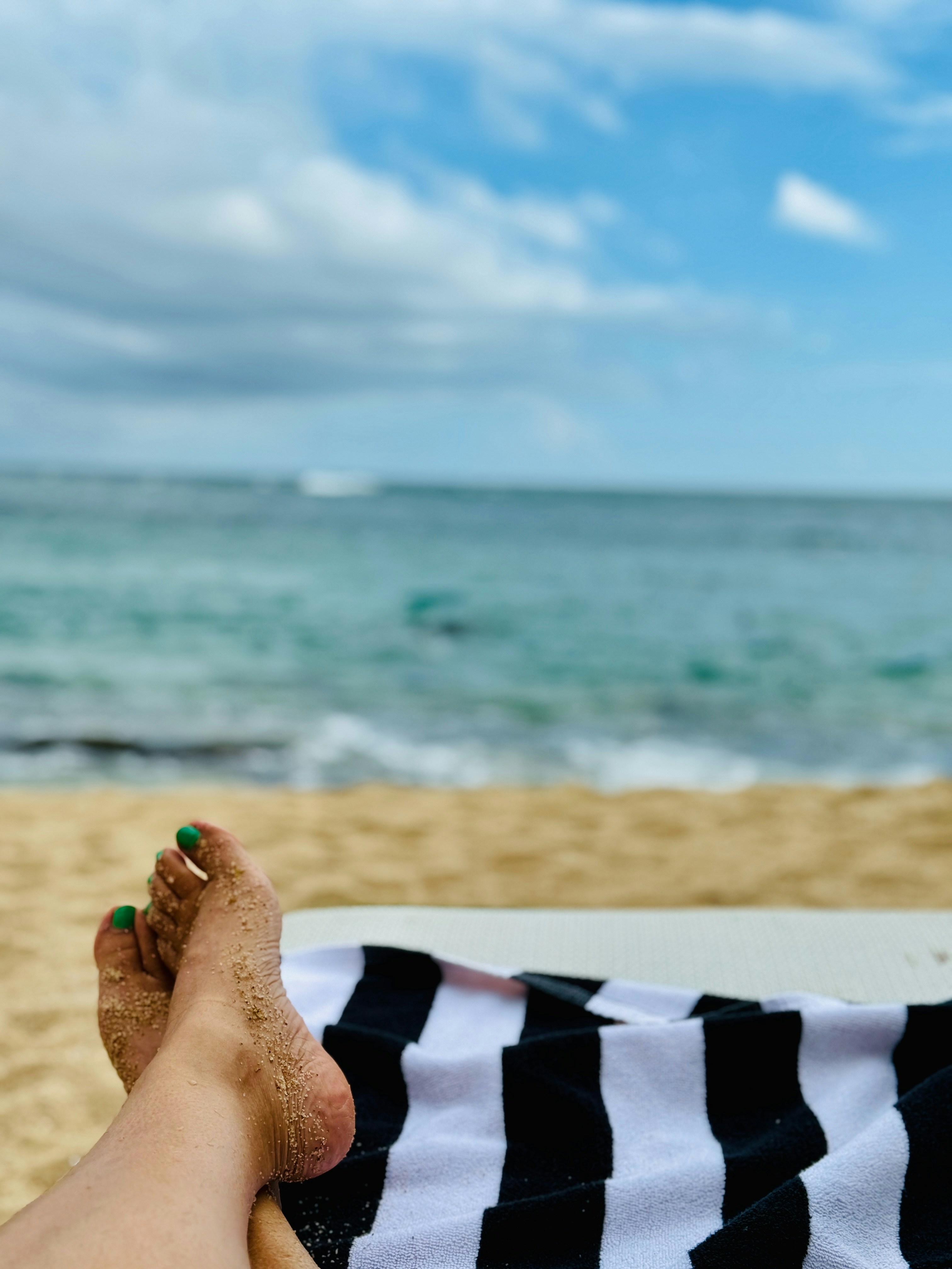 How to Stay Active on Vacation Without Turning It Into a Chore – Feet resting on a beach towel with ocean view.