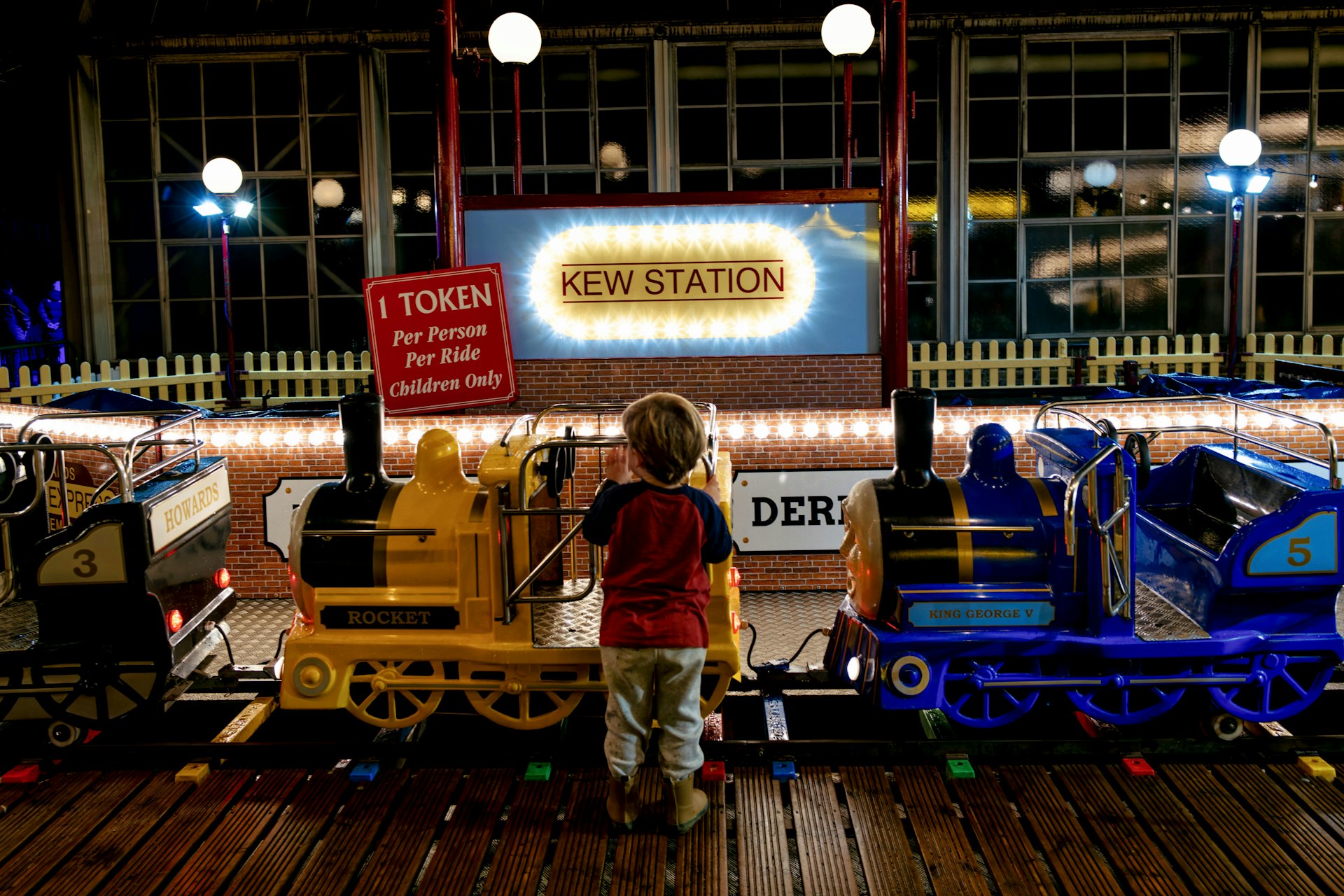 Child looks at toy trains at station
