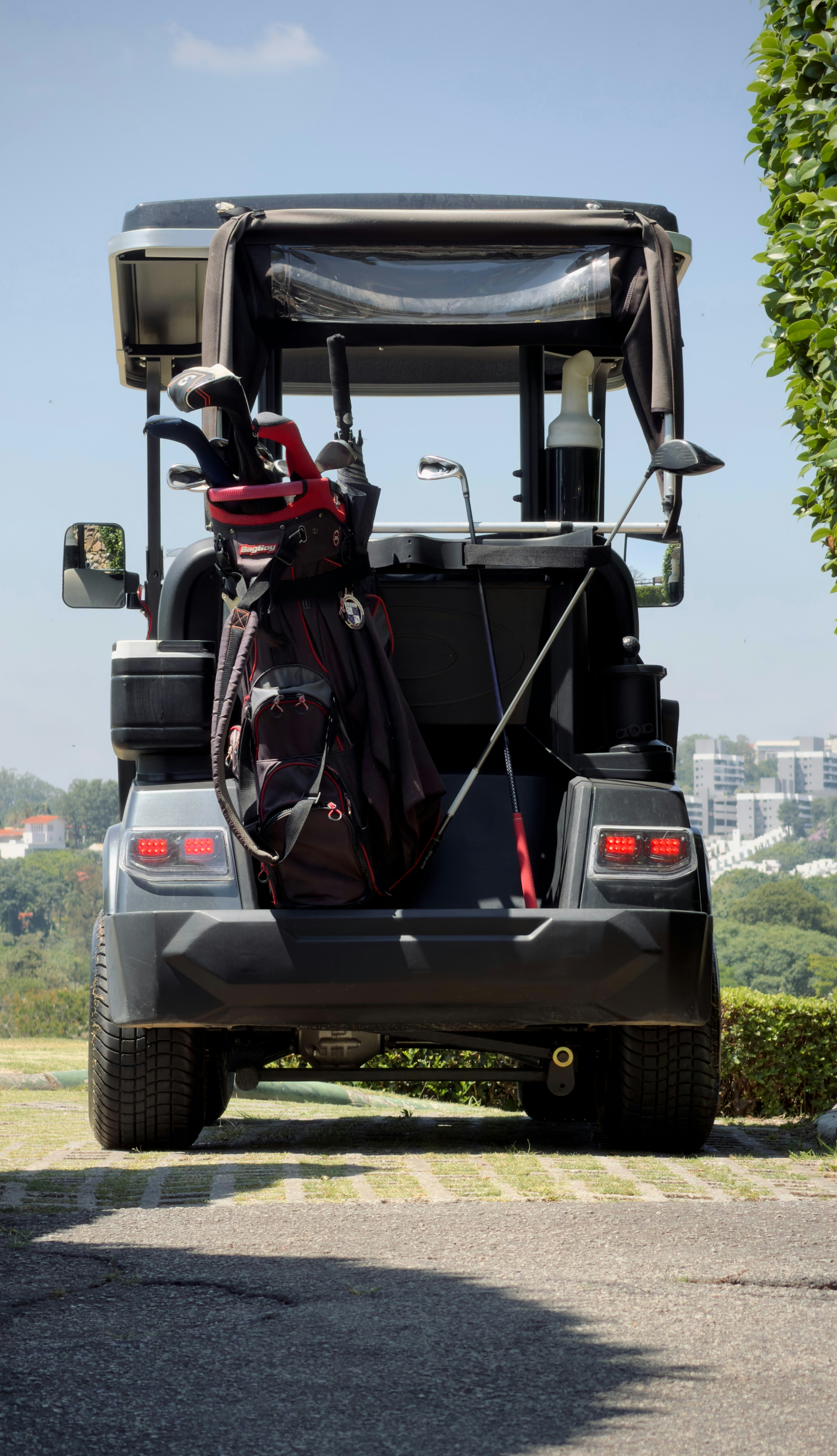 Golf cart with clubs parked on a sunny day.