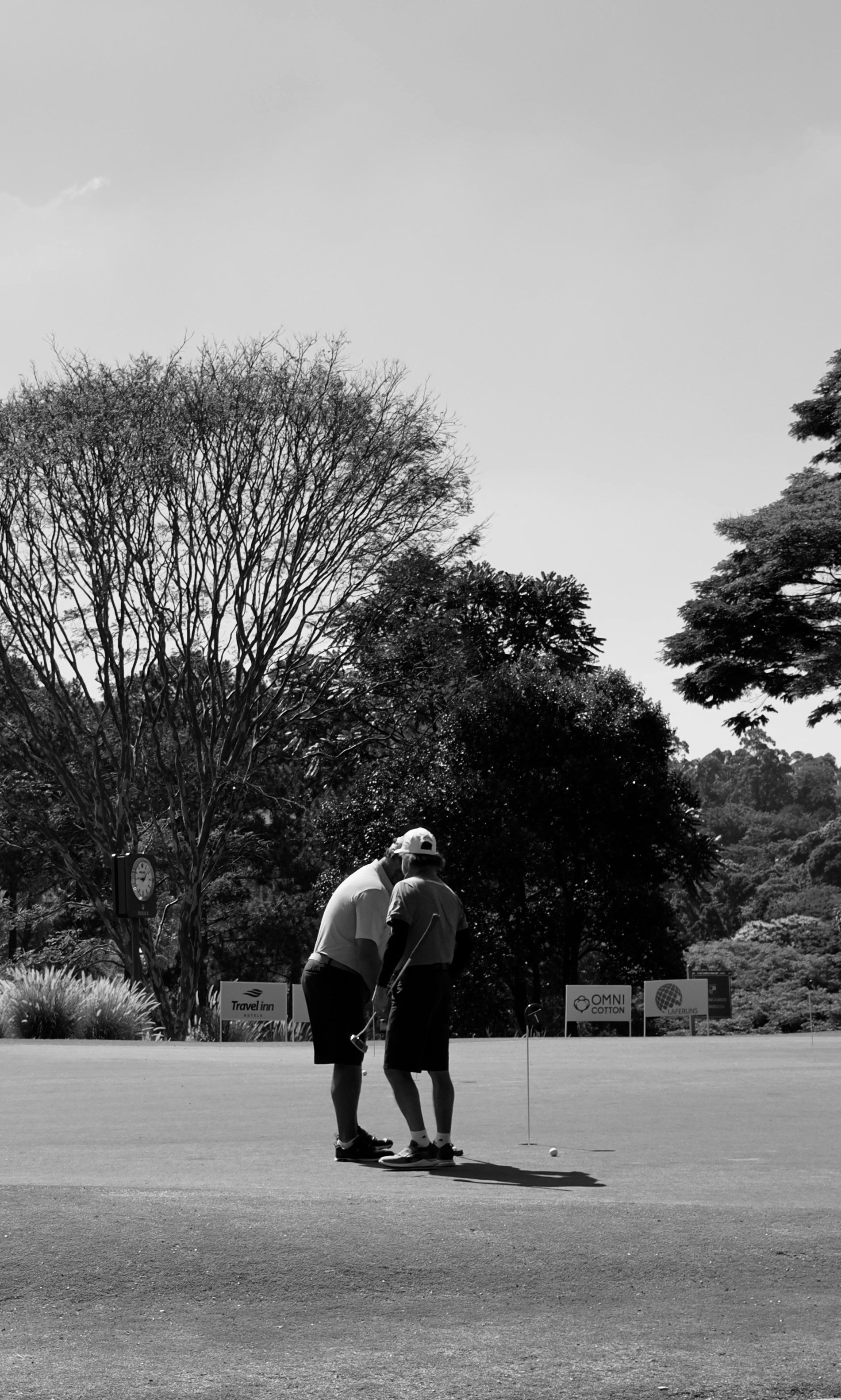 Two golfers on a course with trees in background.