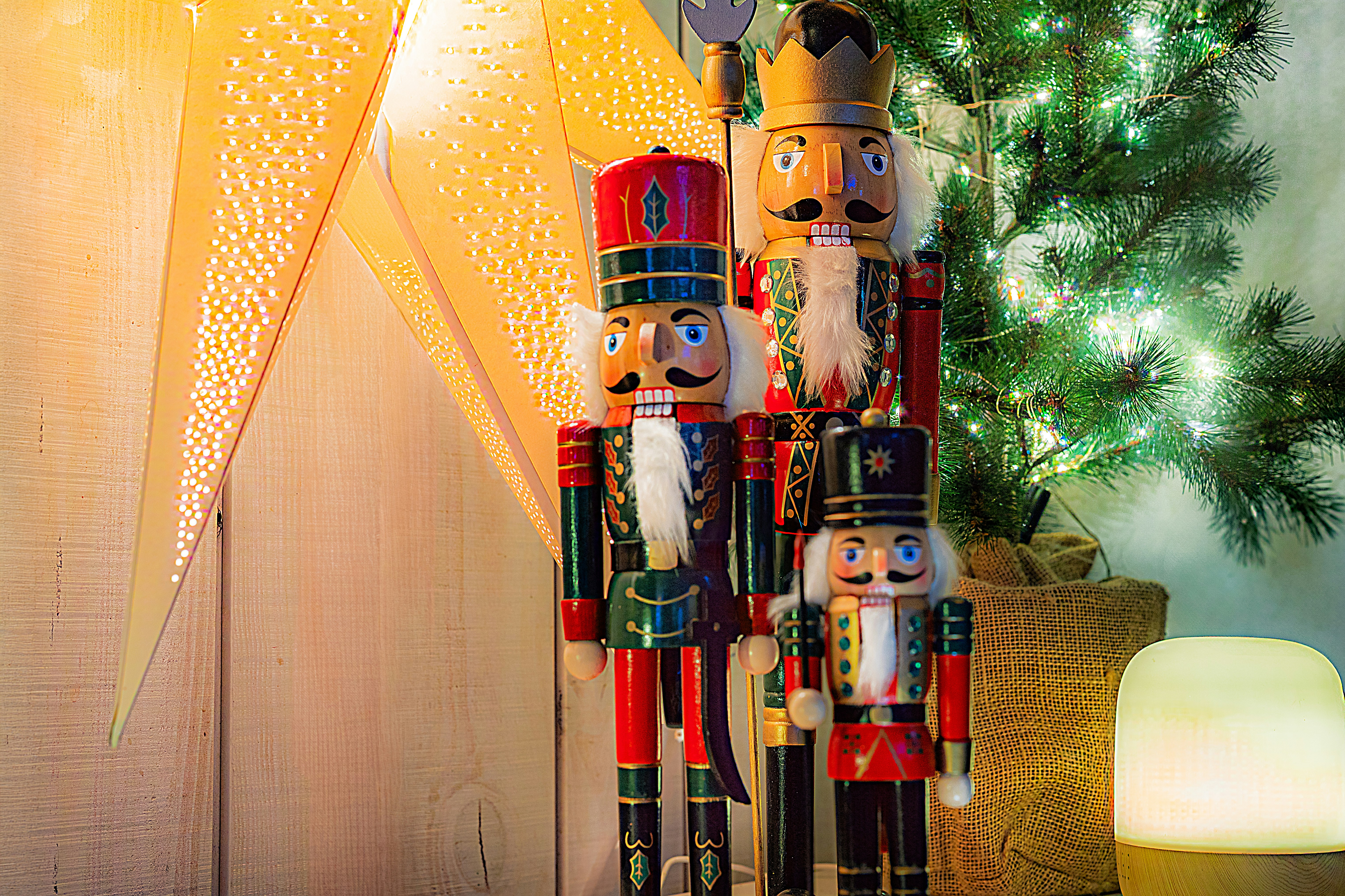 Three nutcracker figures stand by a christmas tree.