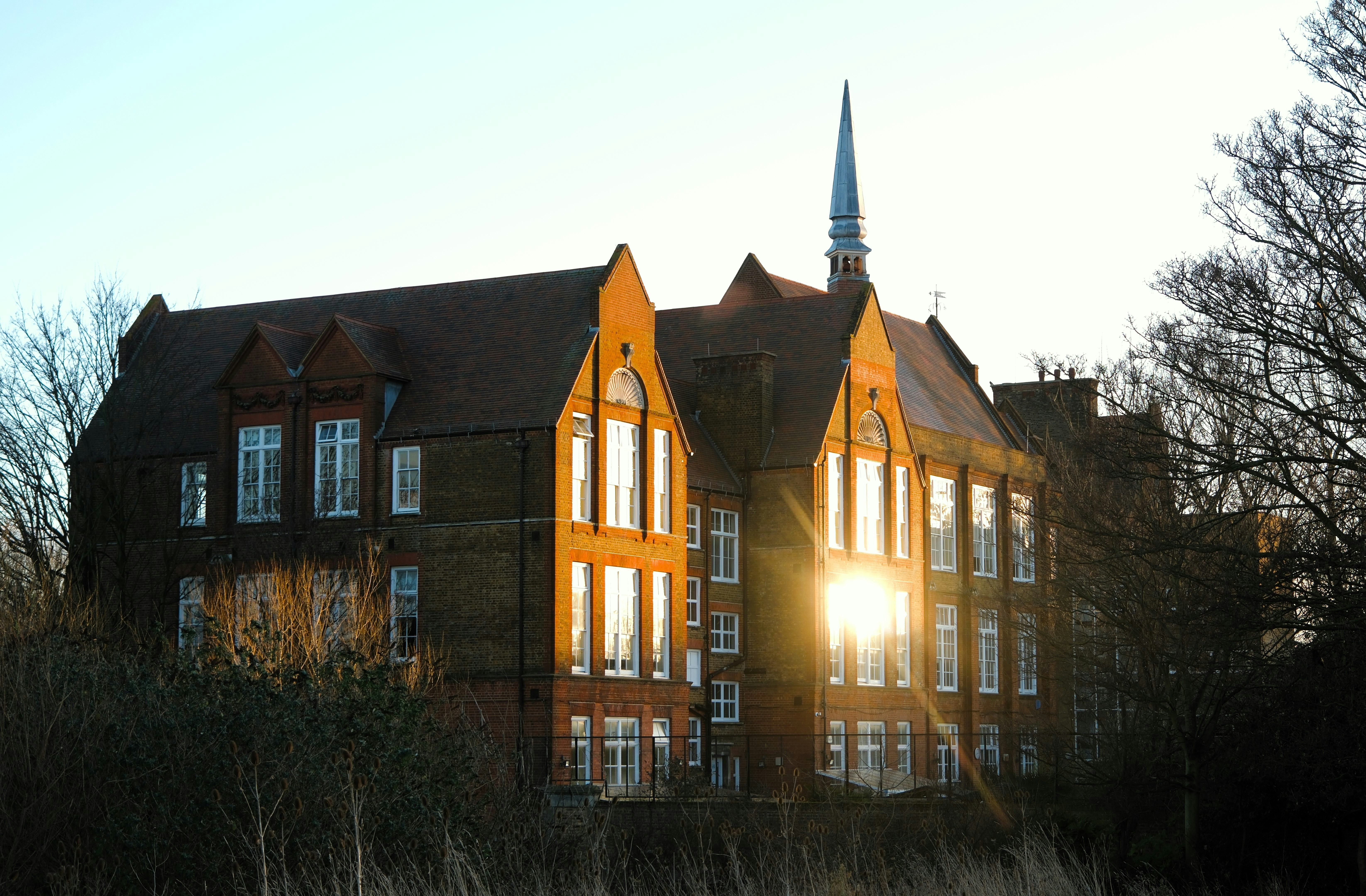 Old brick building with spire at sunset.