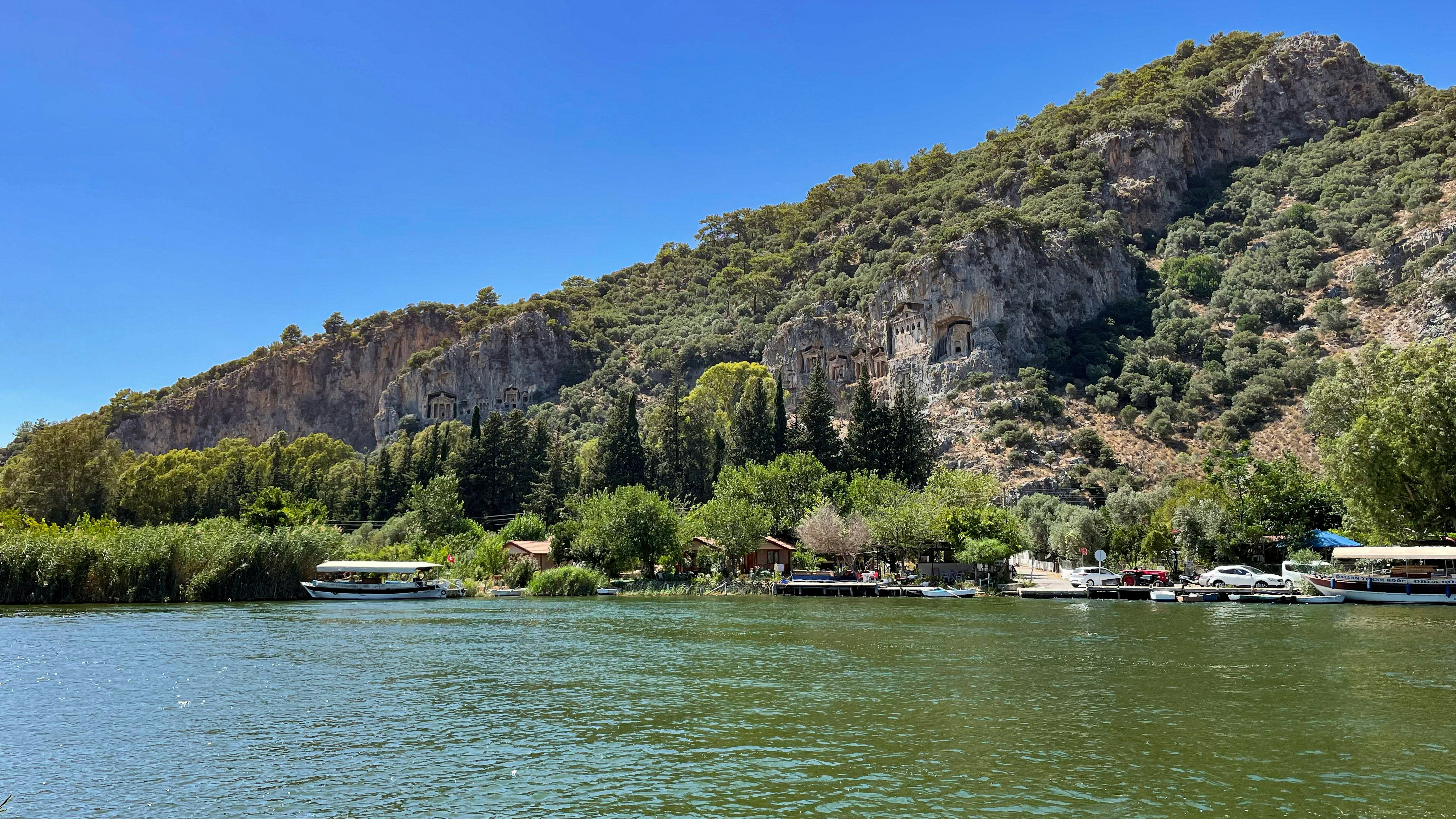 Boats on a wide river with a rocky mountain backdrop