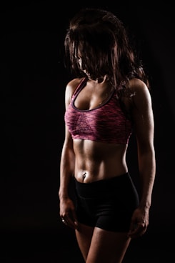 Fit woman in sports bra and shorts on black background