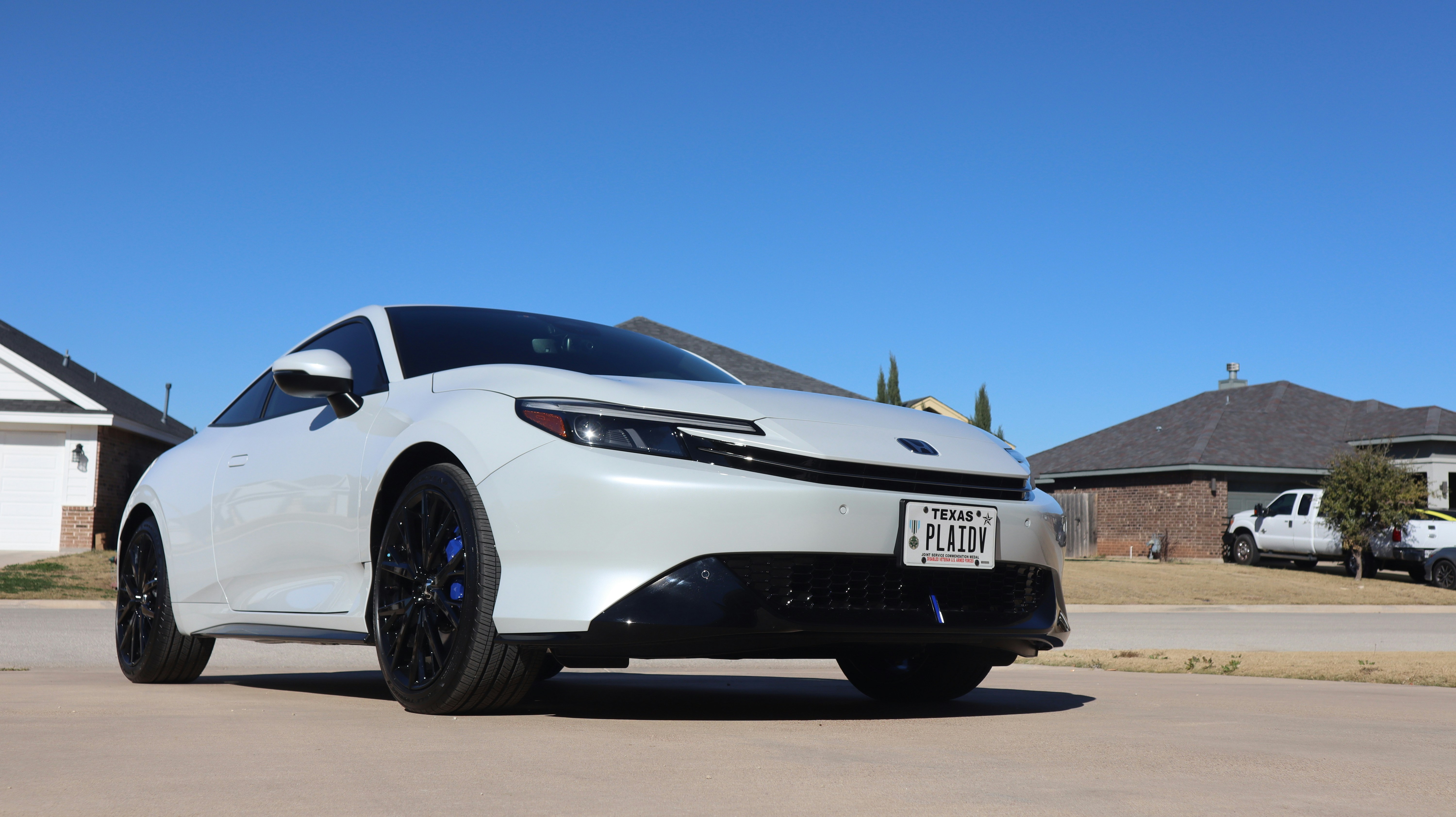 White car parked on suburban street under blue sky
