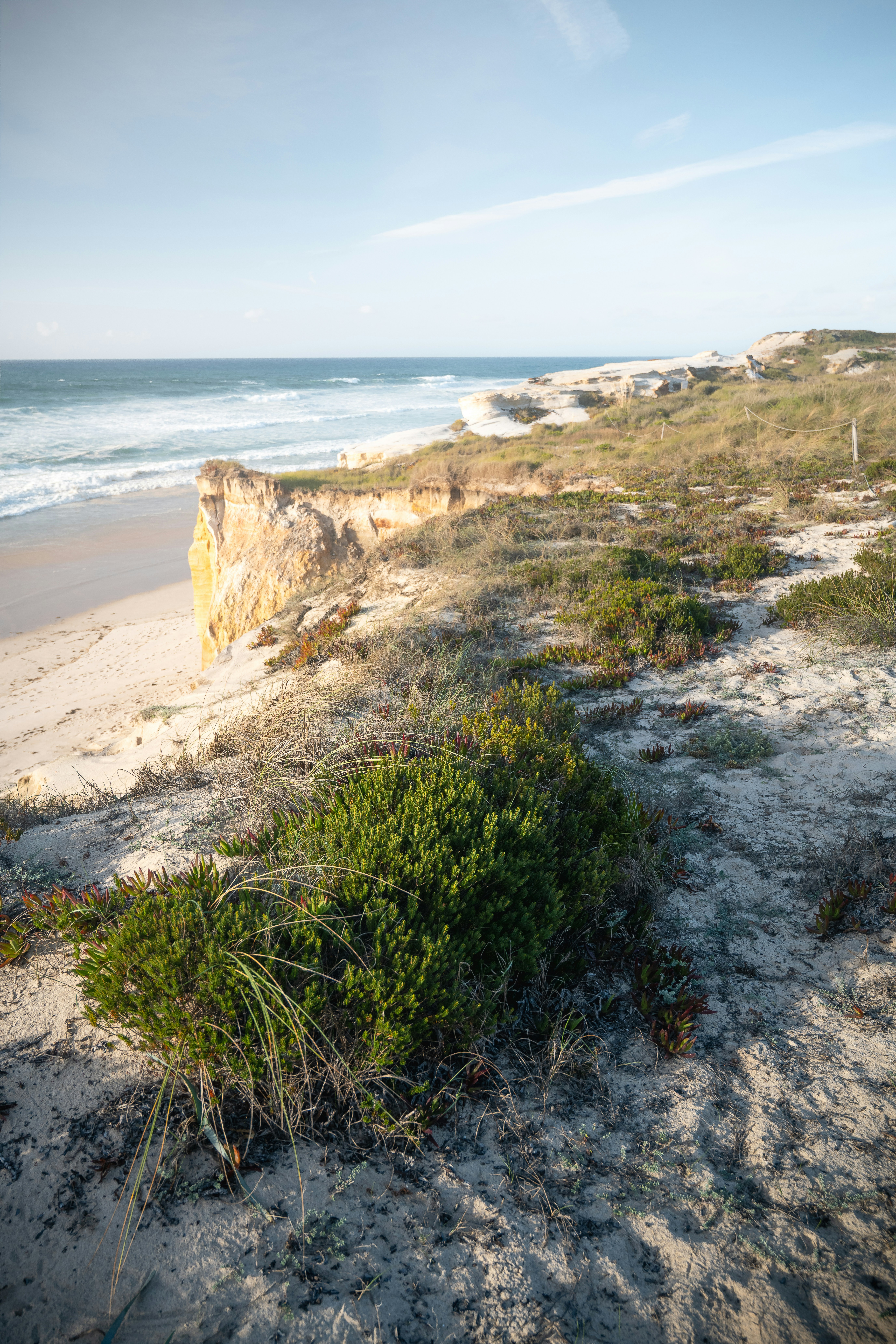 Küstenklippe mit Blick auf einen Sandstrand und den Ozean.