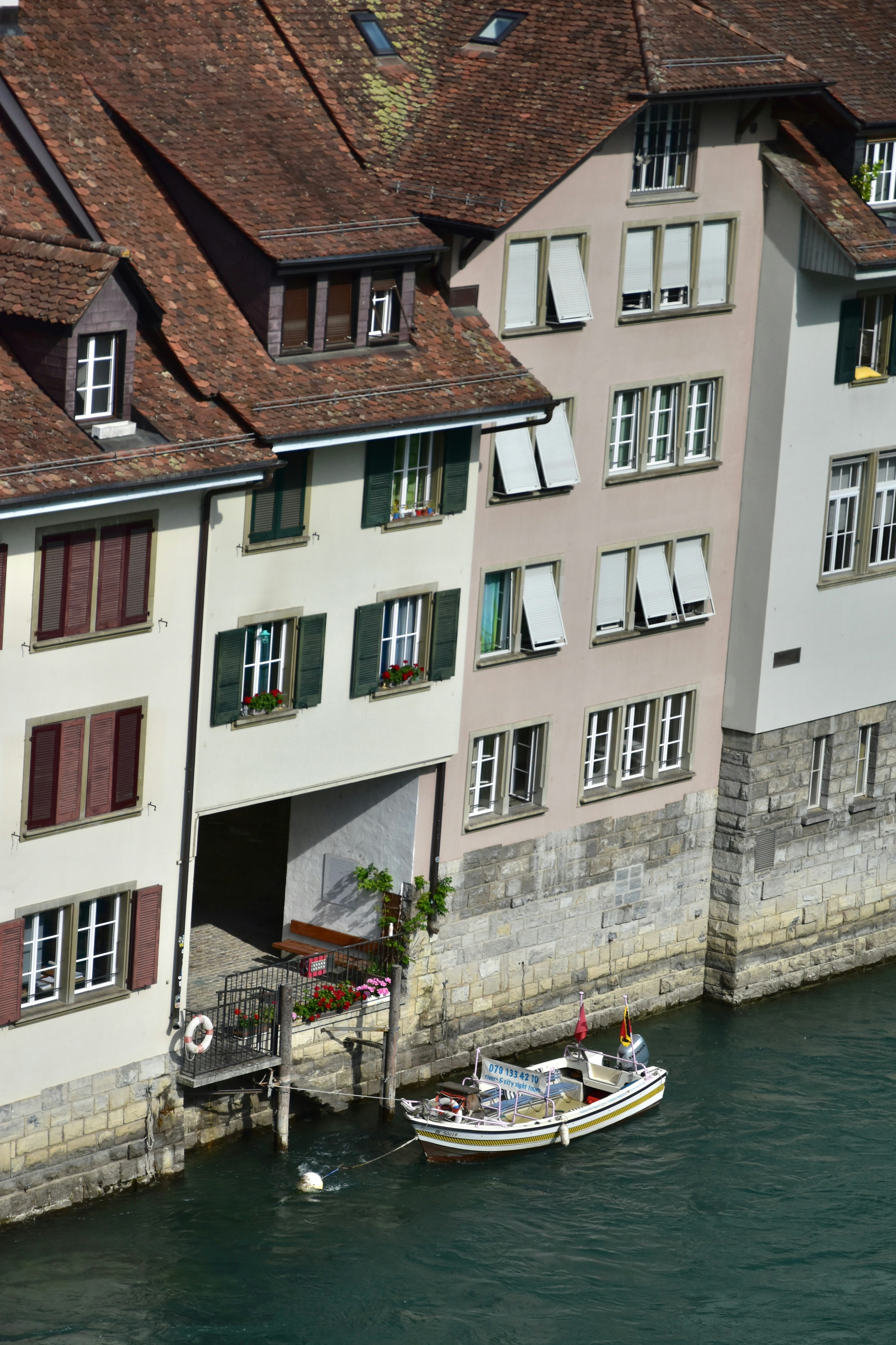 Buildings line a river with a small boat docked.