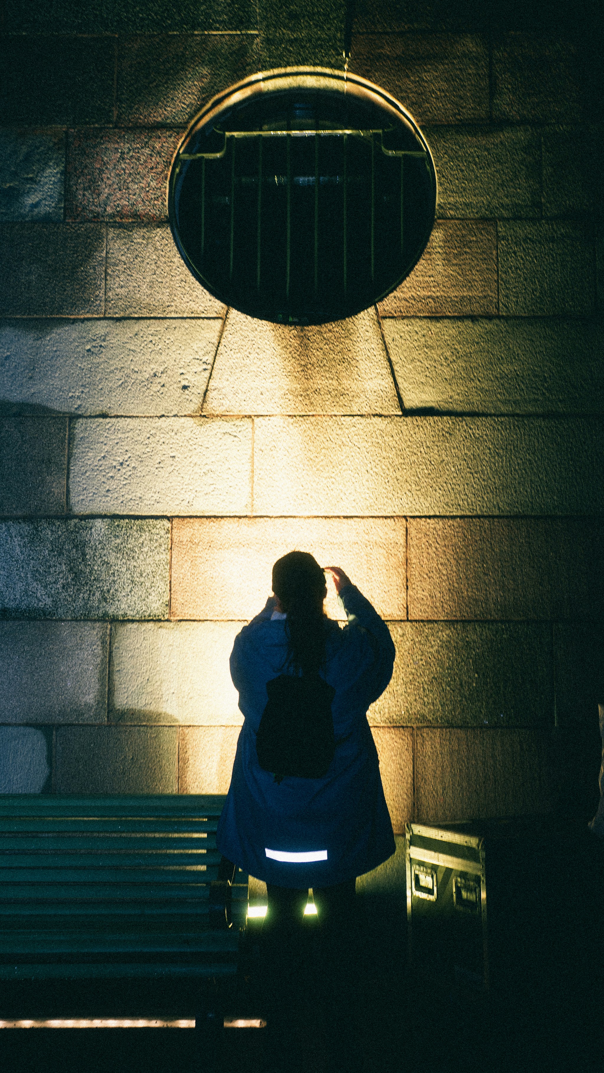 Person looking up at circular vent on stone wall